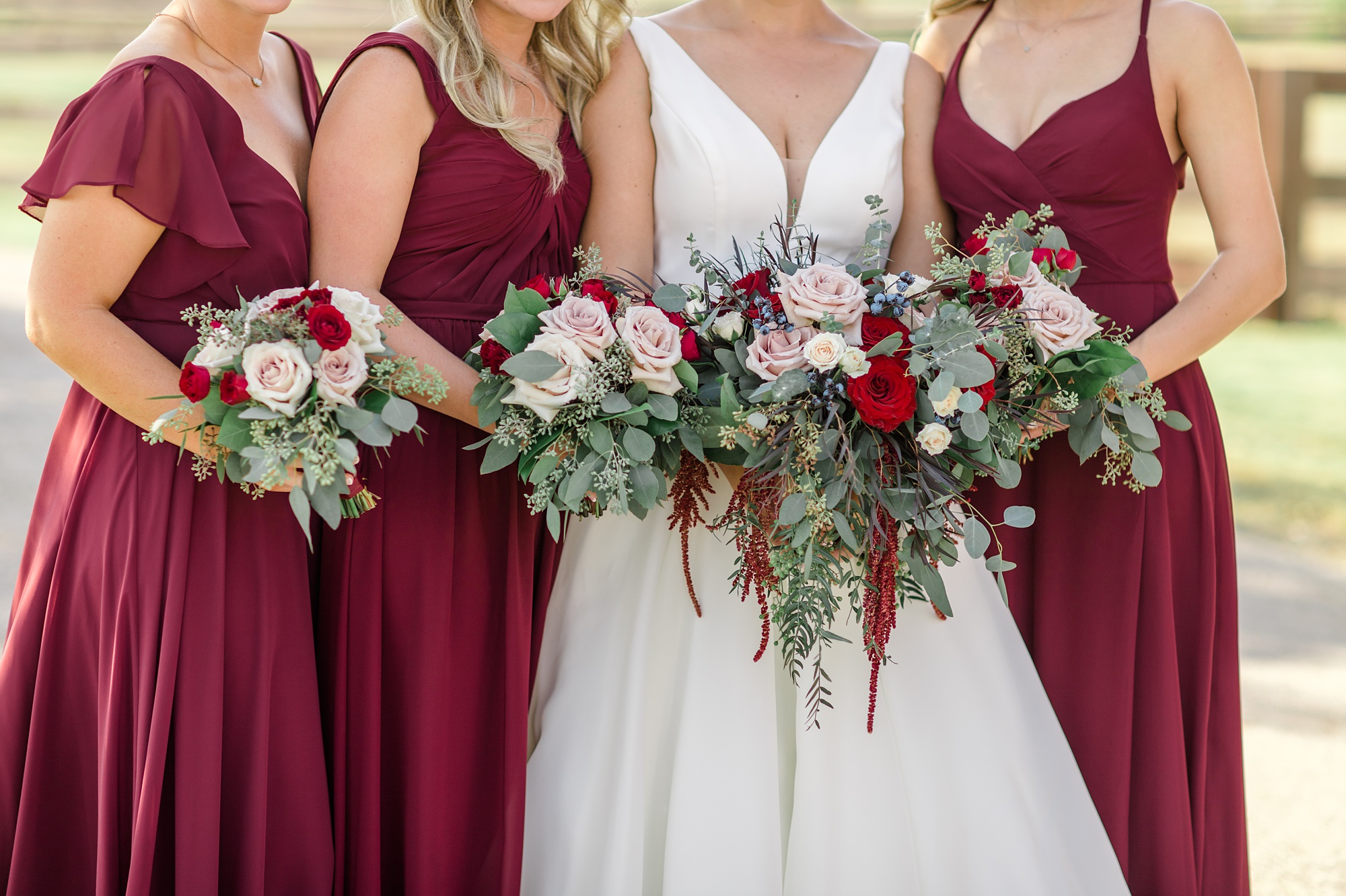 bride poses with bridesmaids in red gowns