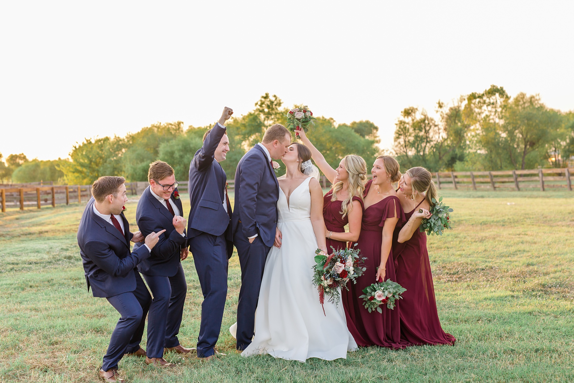 bridal party cheers while bride and groom kiss