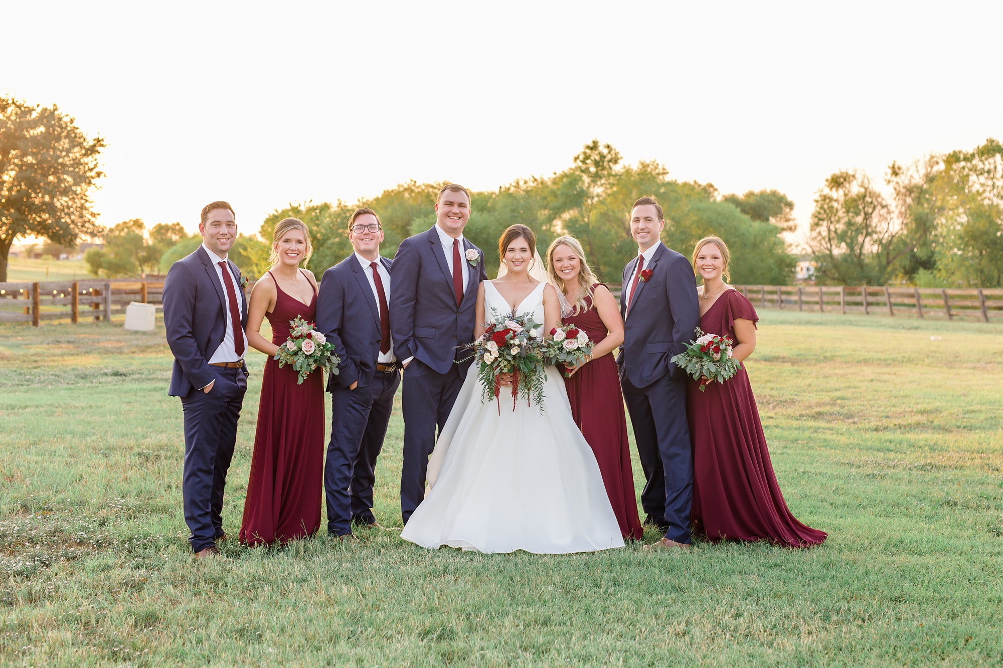 bridal party in navy and cranberry poses with bride and groom