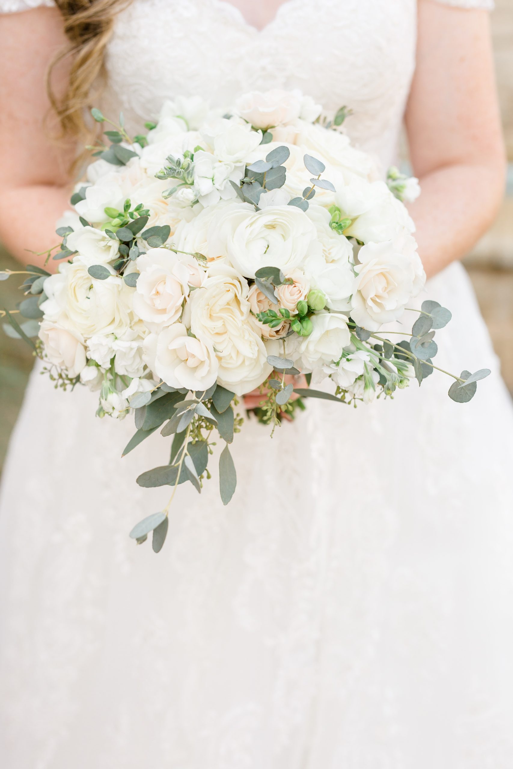 bride holds bouquet of ivory flowers for Hidden Pines Highland Village 
