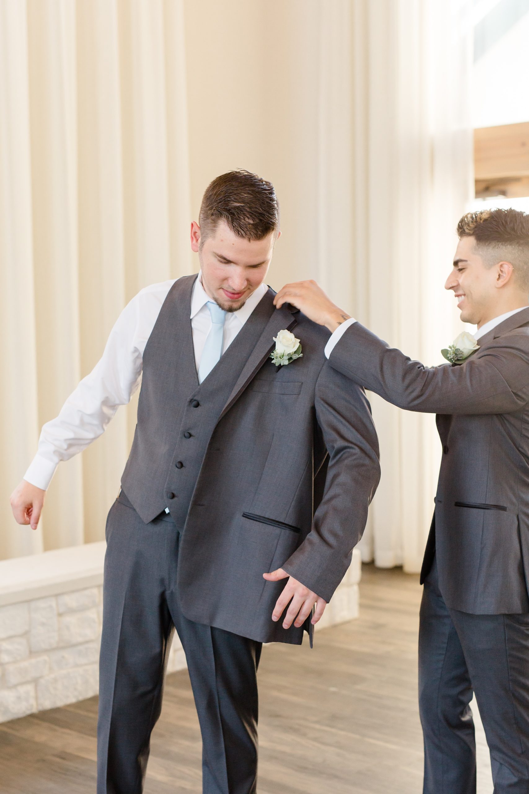 groom puts on jacket during Hidden Pines Highland Village wedding