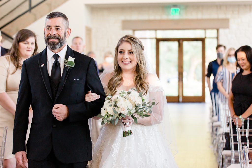 bride walks up aisle with father at Hidden Pines Highland Village