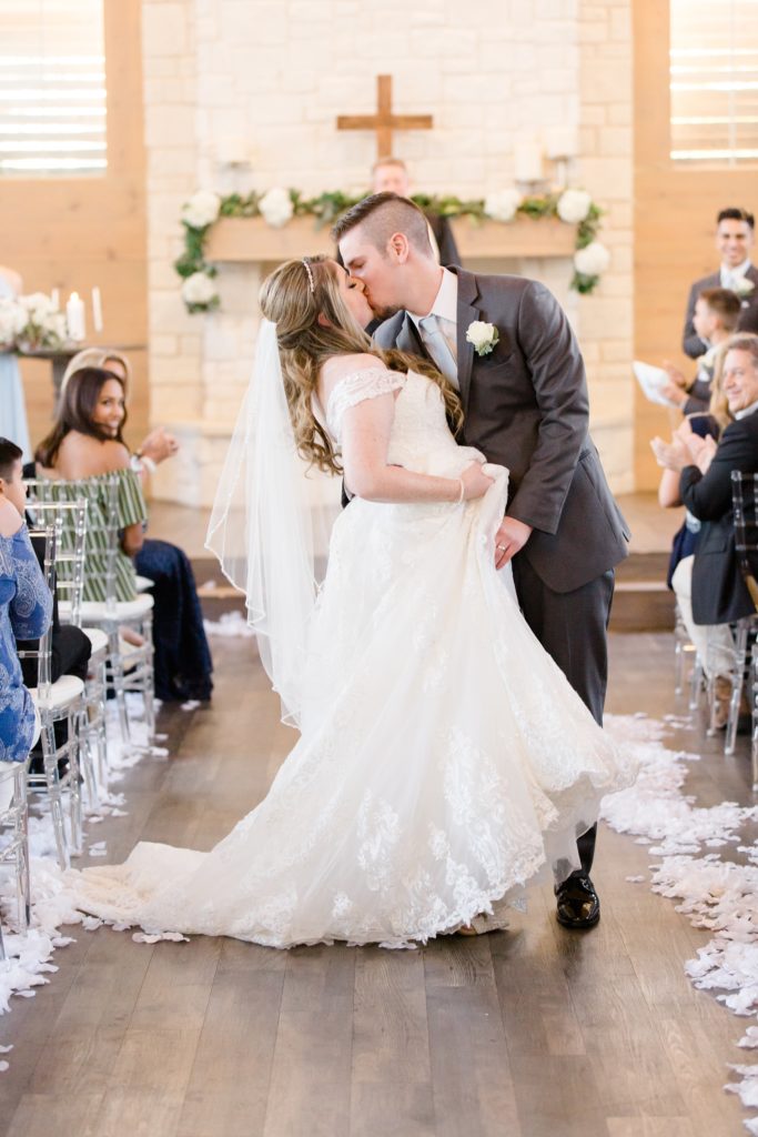 bride and groom kiss at end of aisle