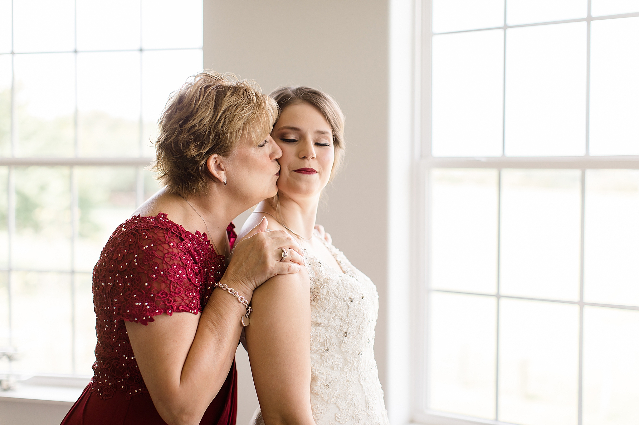 mom gives bride a kiss on the cheek during wedding prep