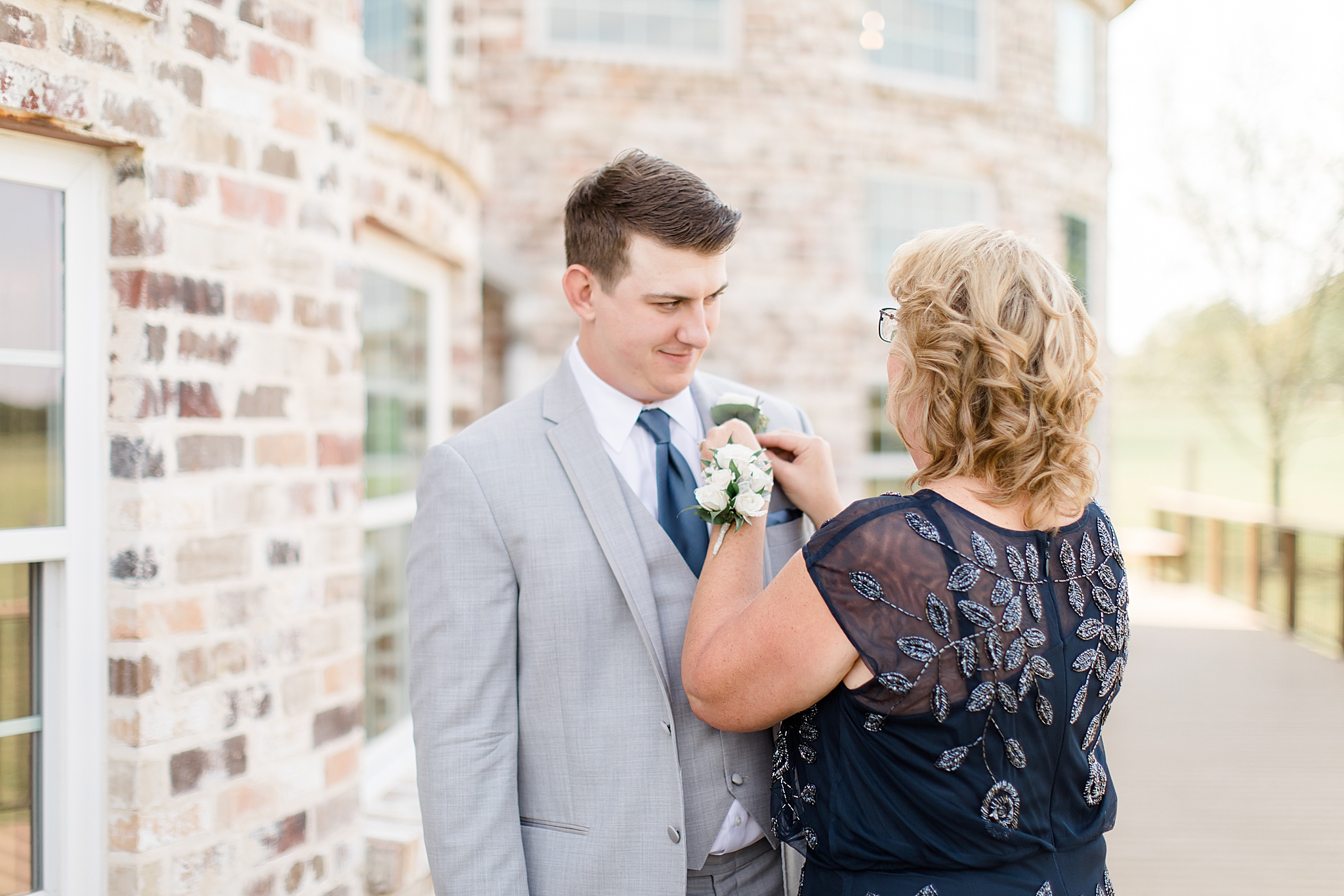 mother of the groom adjusts boutonnière before Rustic Grace Estate wedding