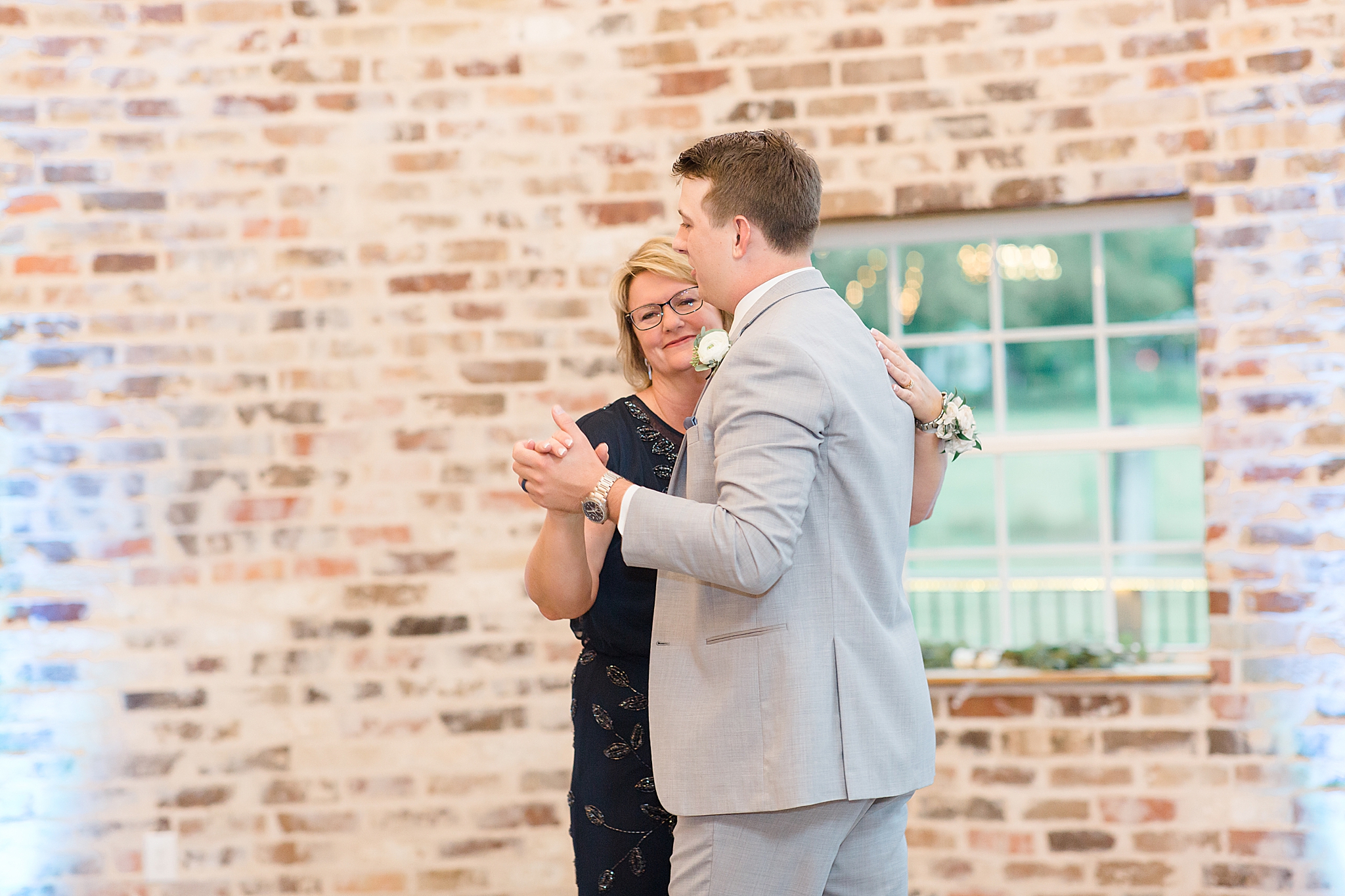 groom and mom dance together during Rustic Grace Estate wedding reception
