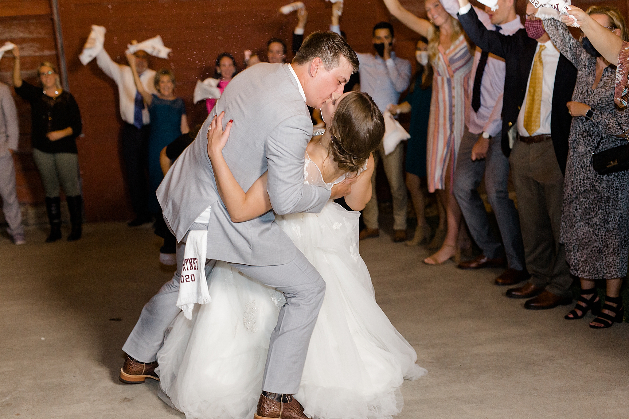 groom kisses bride during sendoff after Rustic Grace Estate wedding with custom towels