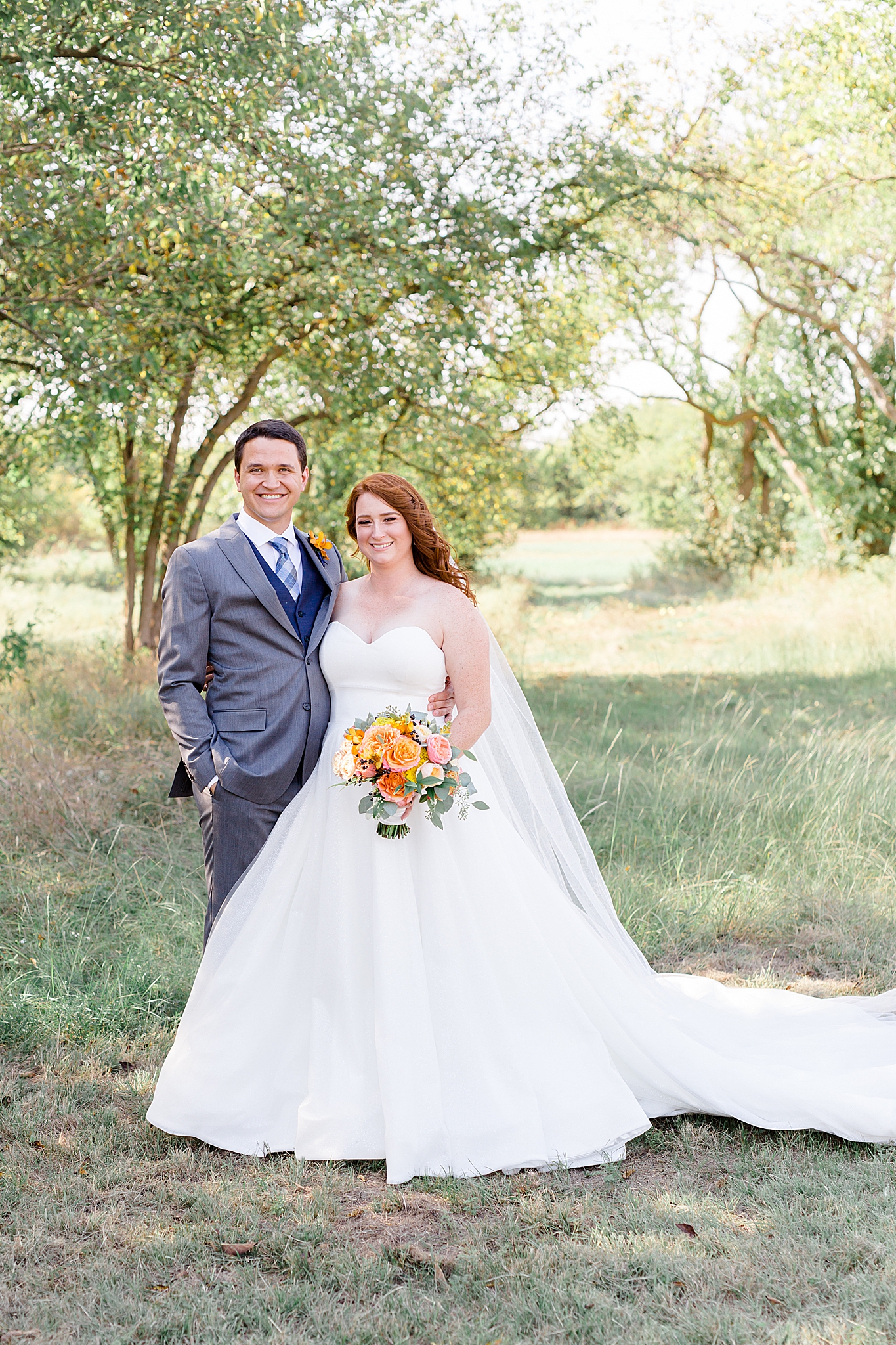 newlyweds pose in shade under tree