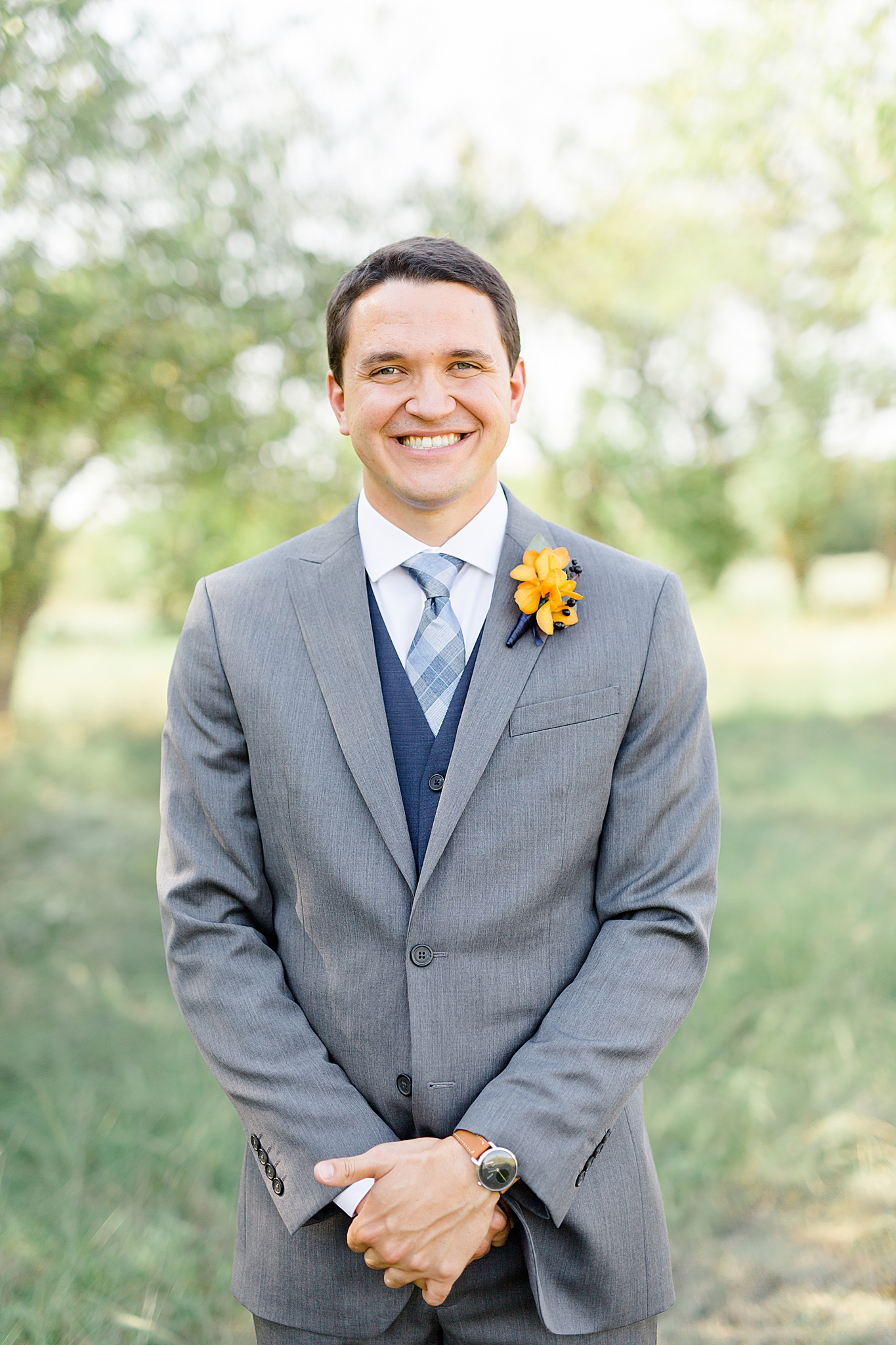 groom in grey suit with navy vest poses at The Nest at Ruth Farms