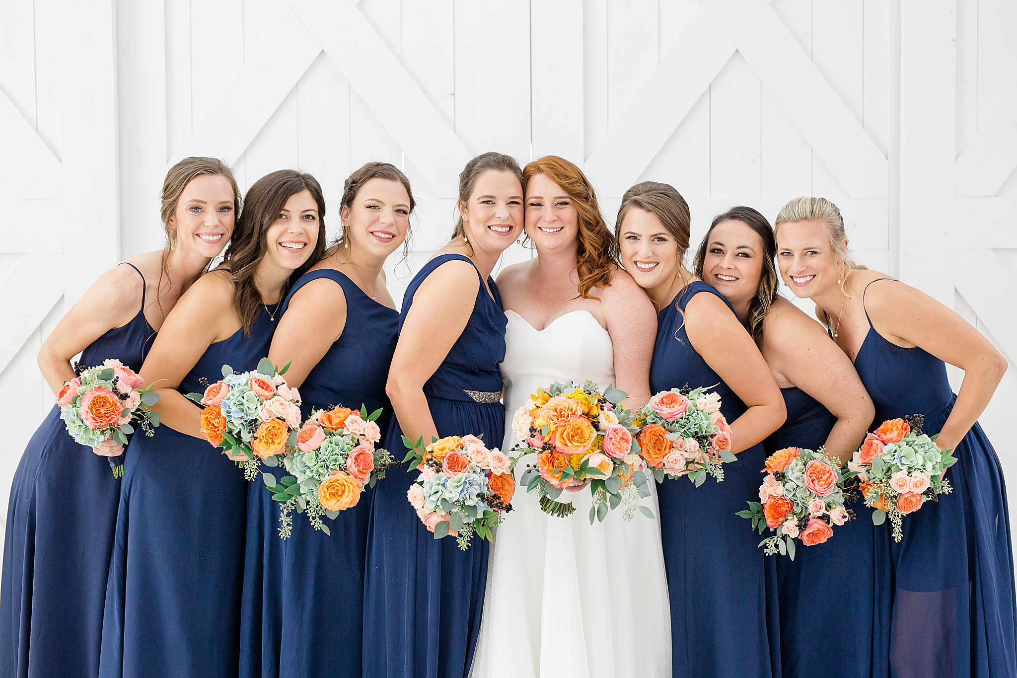 bride poses with bridesmaids in navy gowns