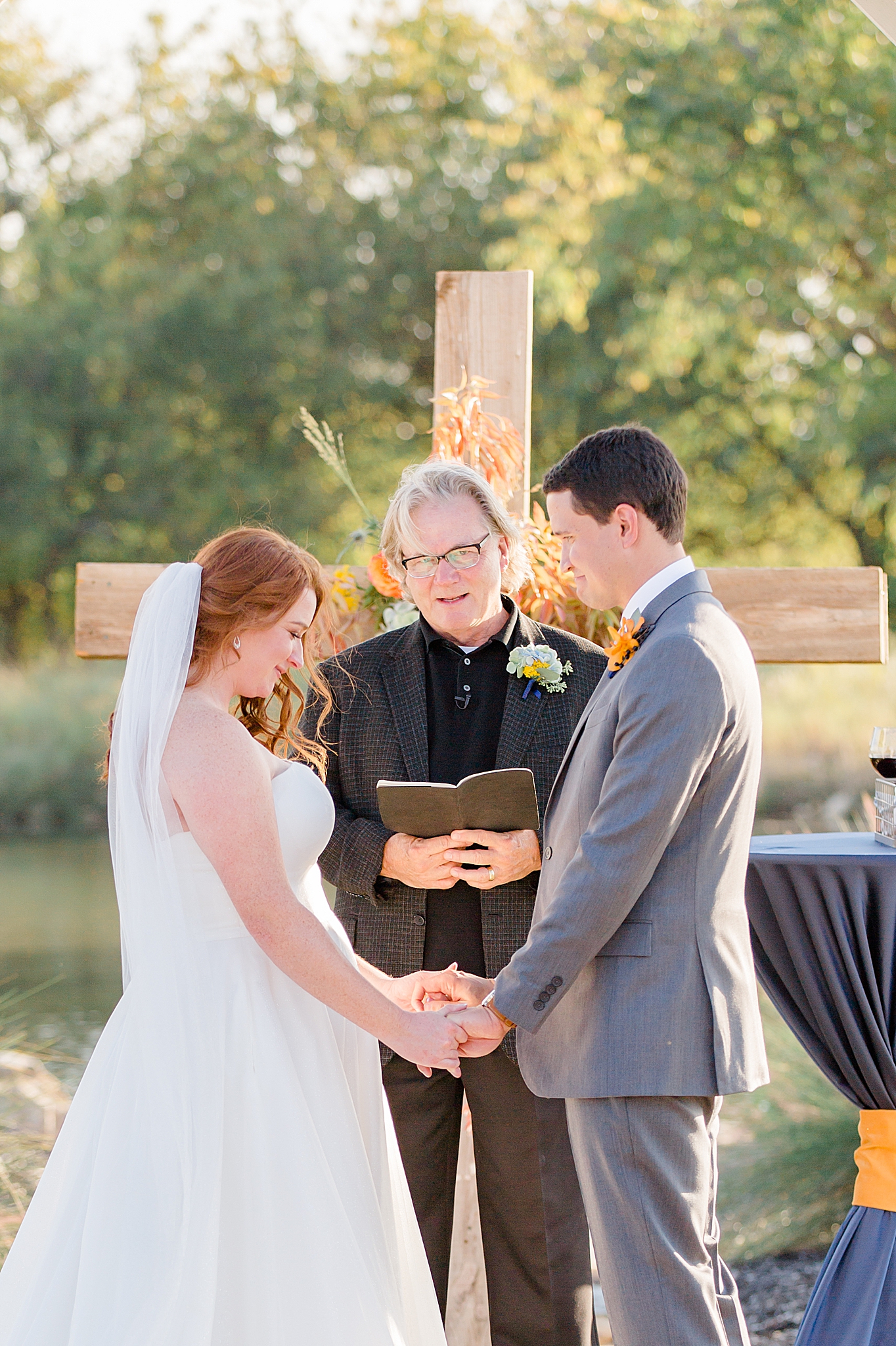 bride and groom pray by wooden cross at The Nest at Ruth Farms