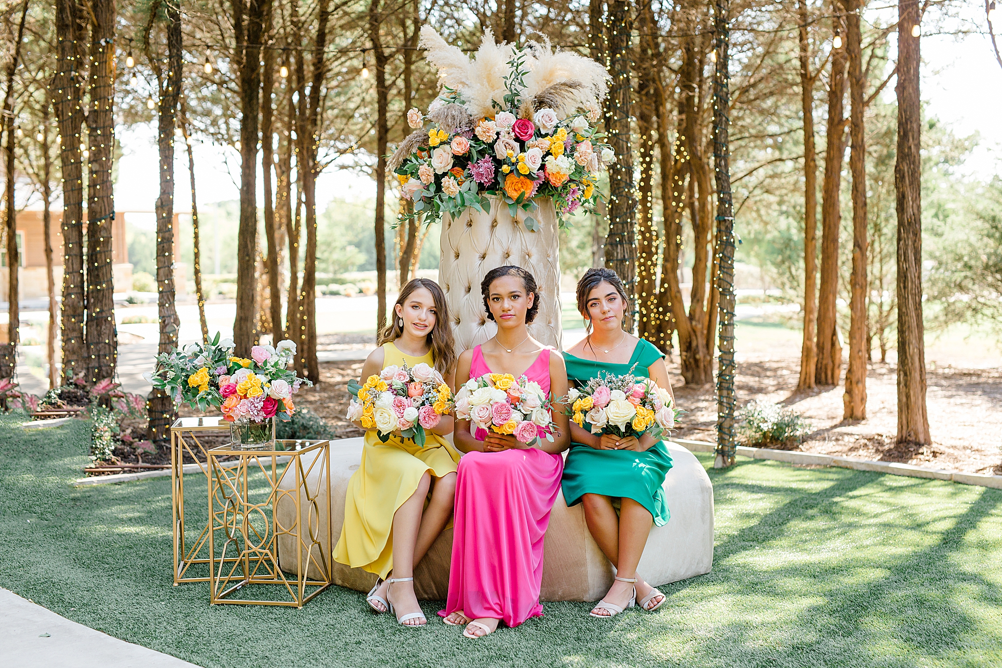 three junior bridesmaids in bright colors sit on floral display