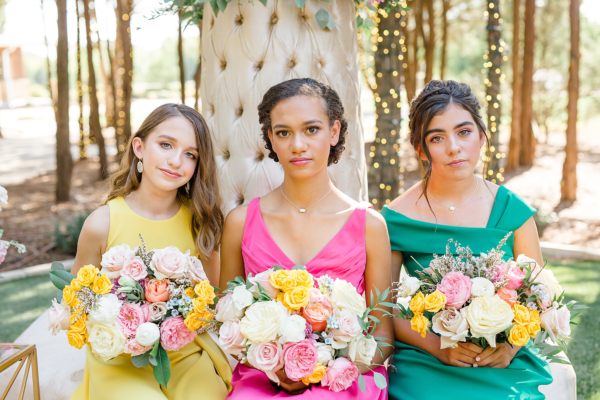 three bridesmaids pose on floral display in Texas