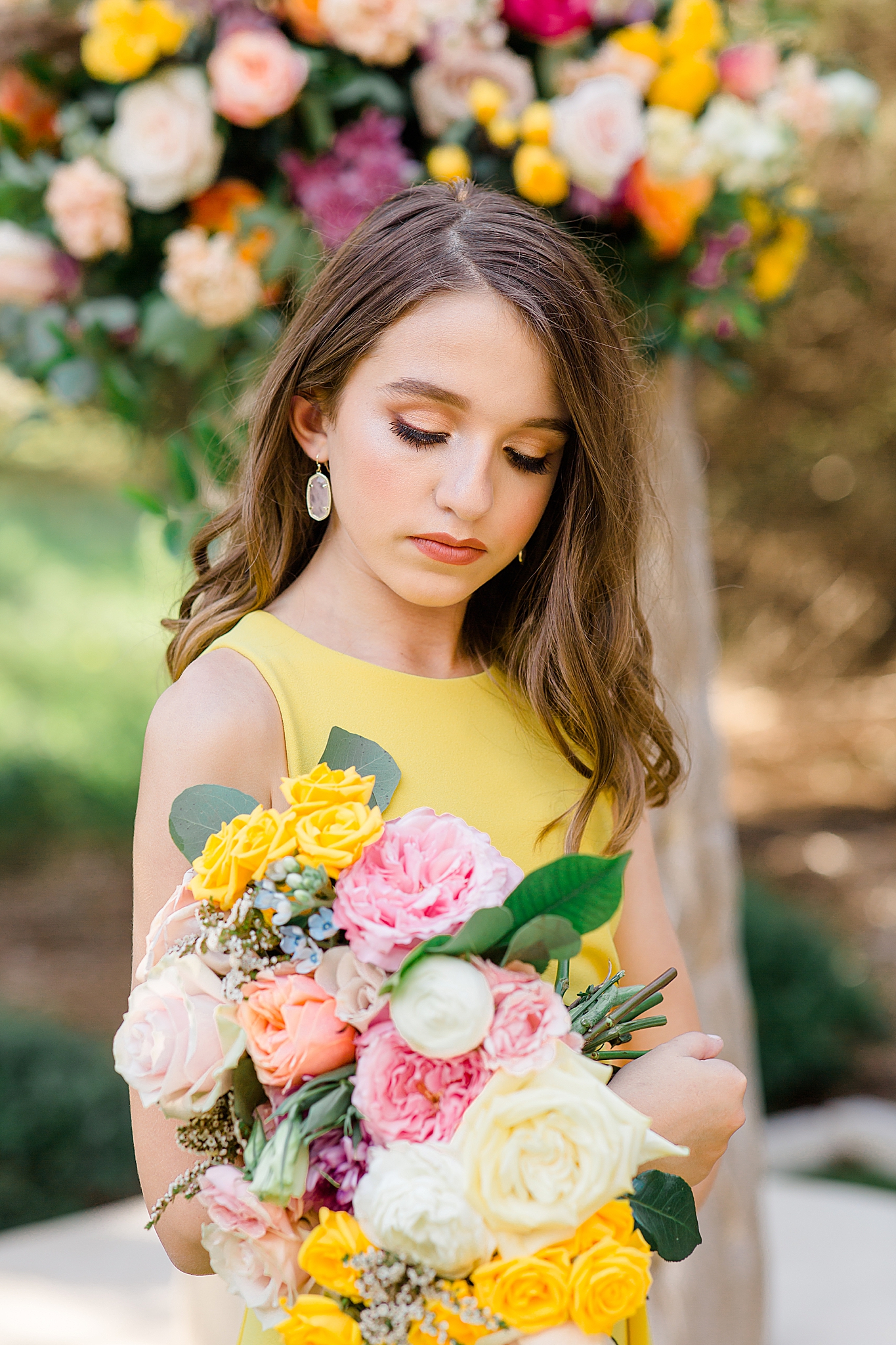 junior bridesmaid in yellow gown holds bouquet for flowers