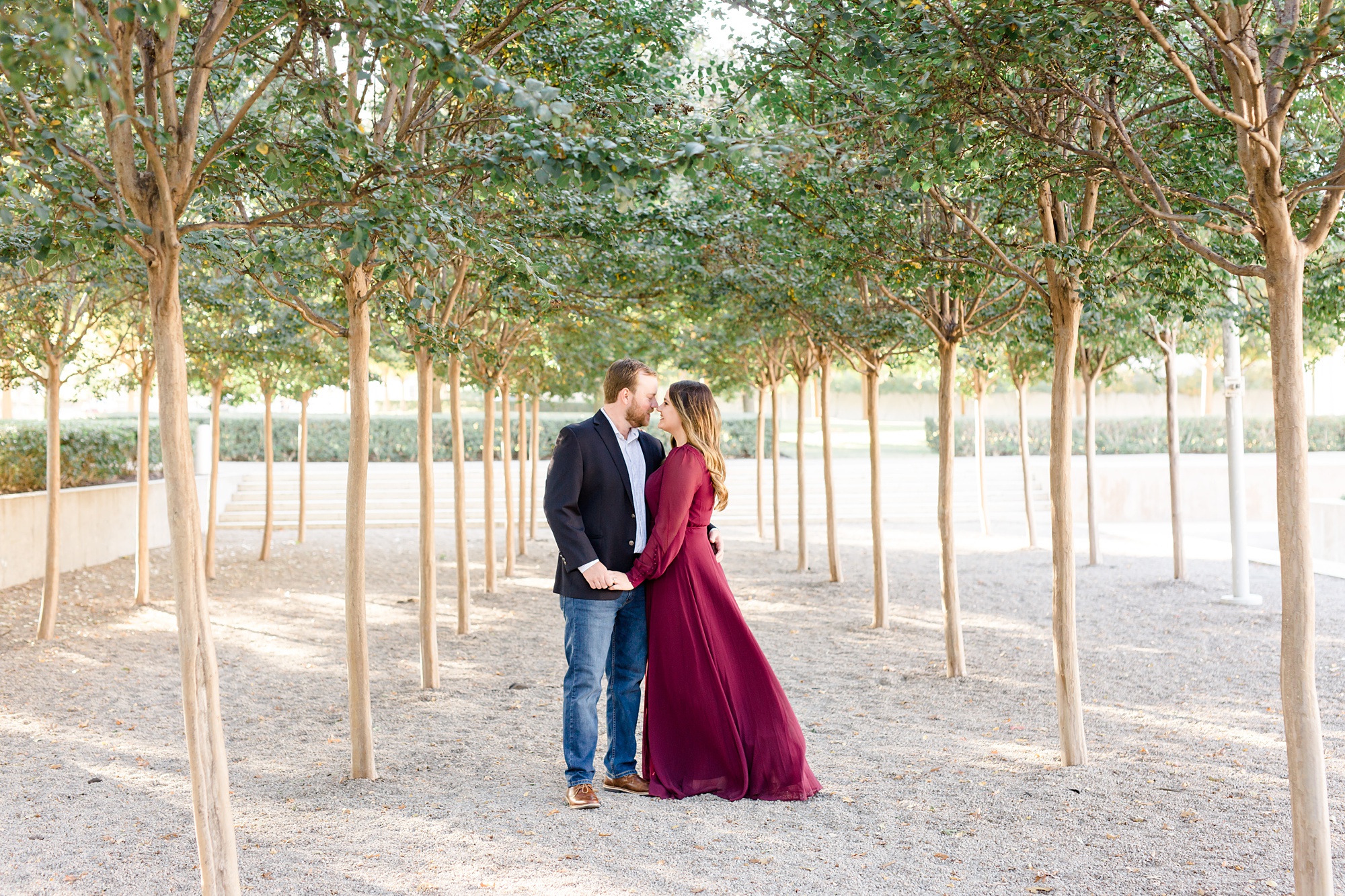engaged couple stands in grove of trees