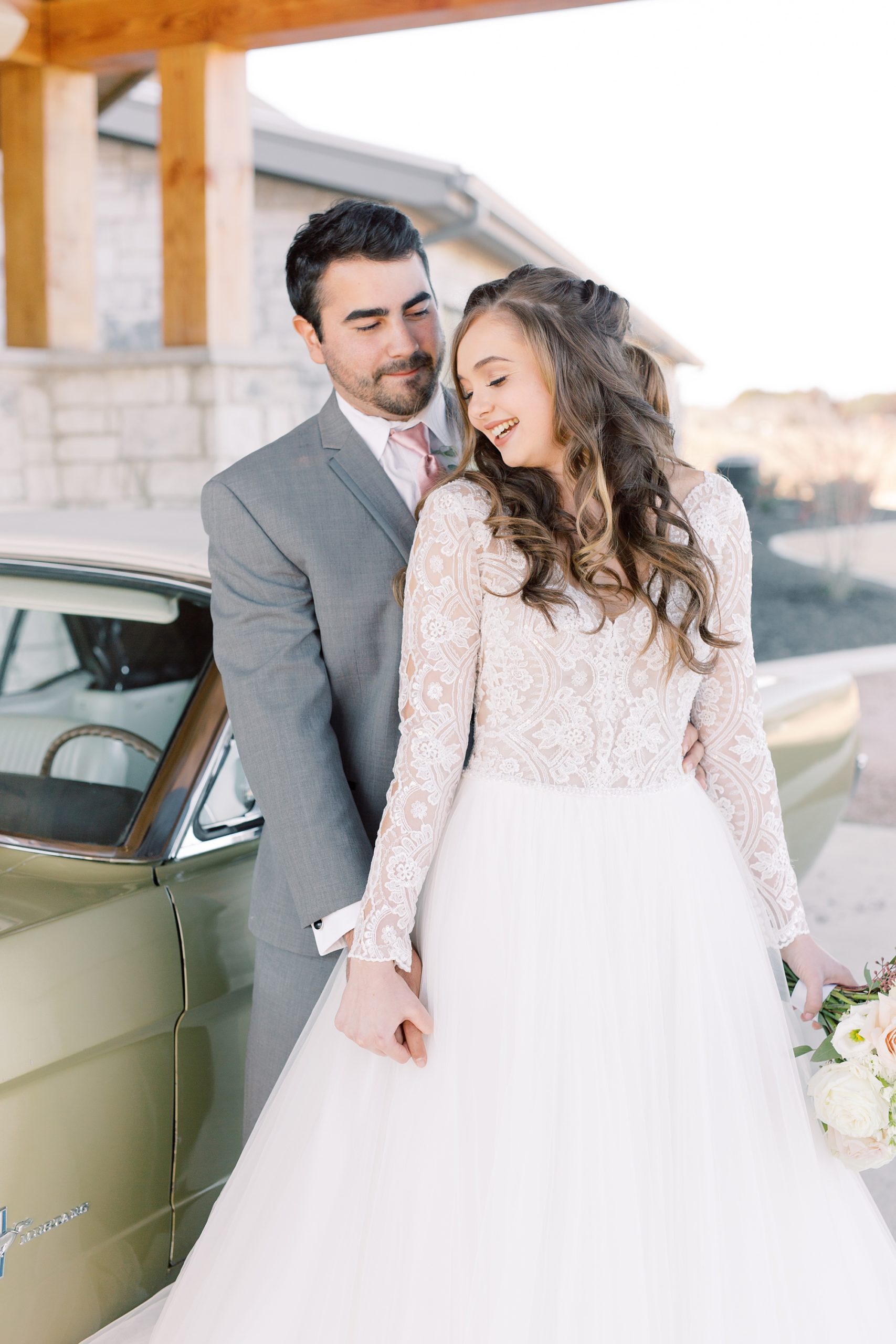 bride and groom laugh by car in Texas