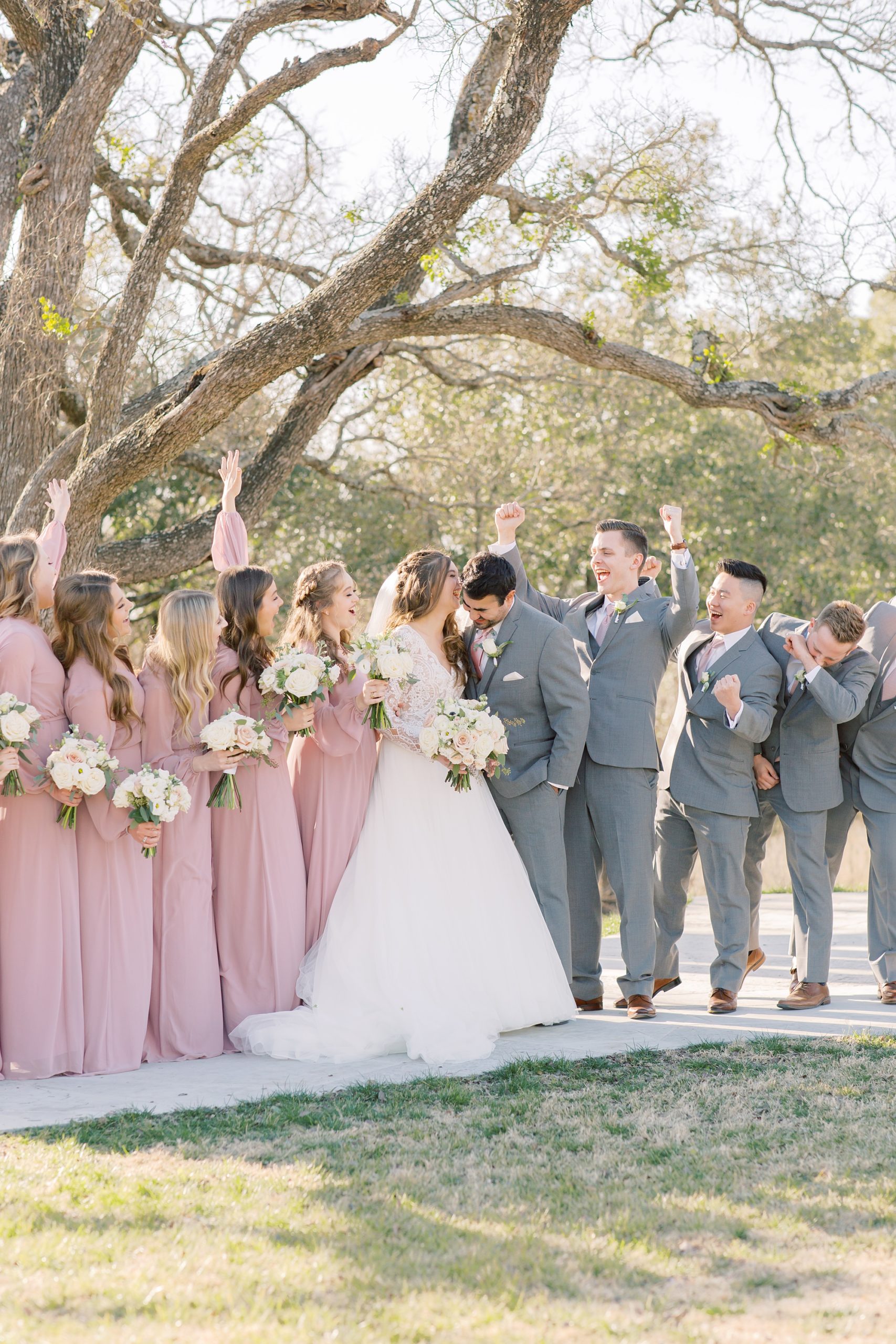 bride and groom kiss while bridal party cheers 