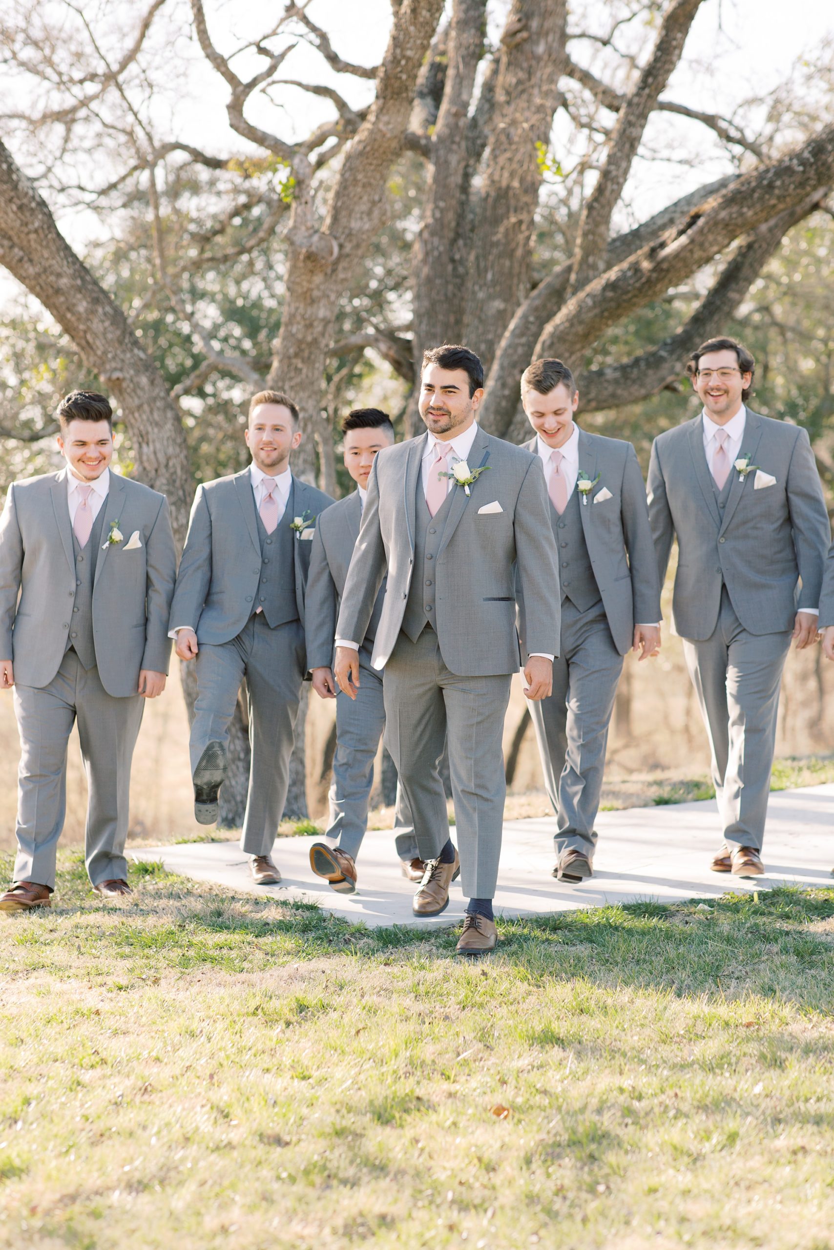 groom and groomsmen in grey suits walk along path at HighPointe Estate