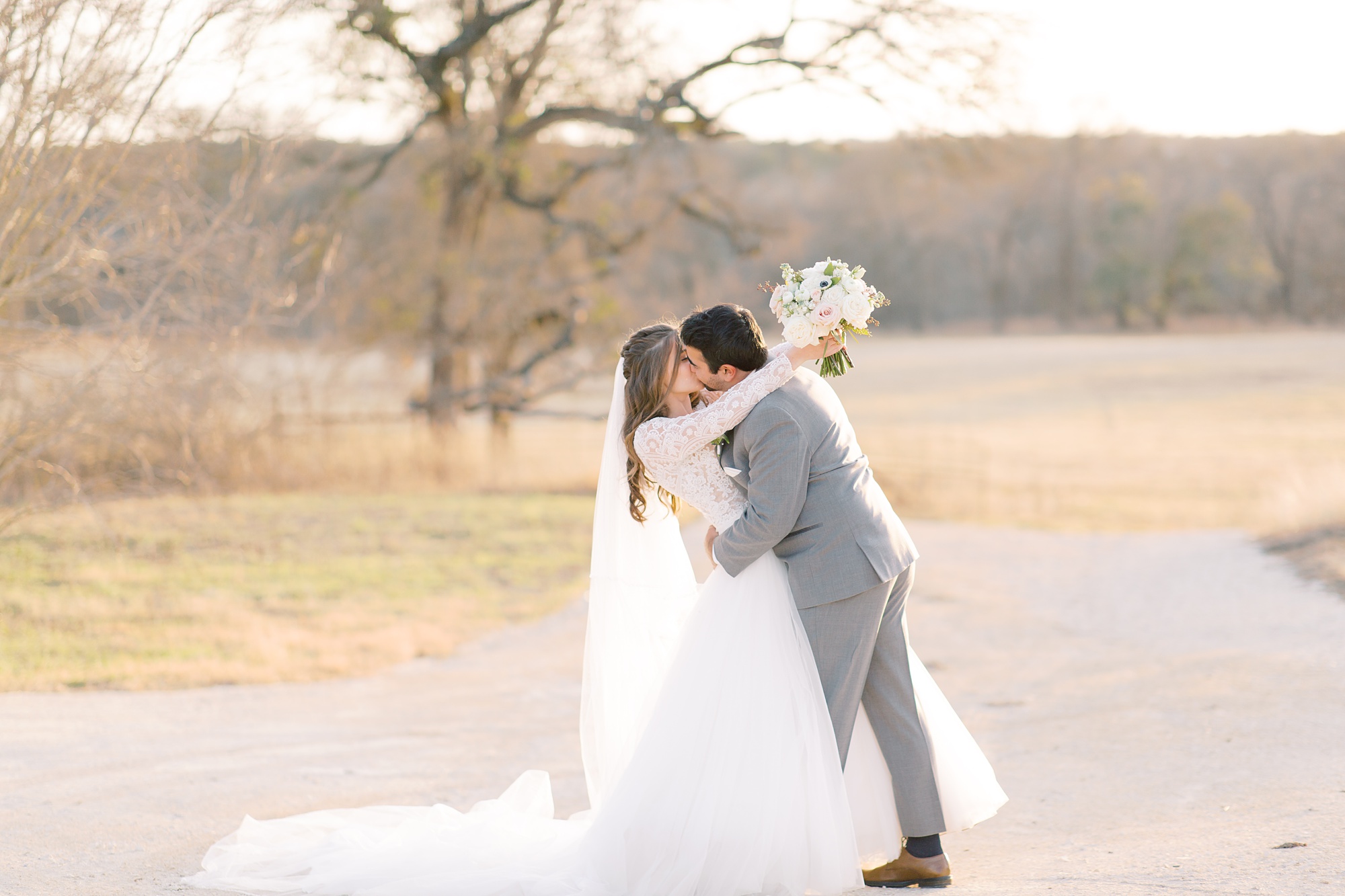 groom hugs and kisses bride during photos at sunset