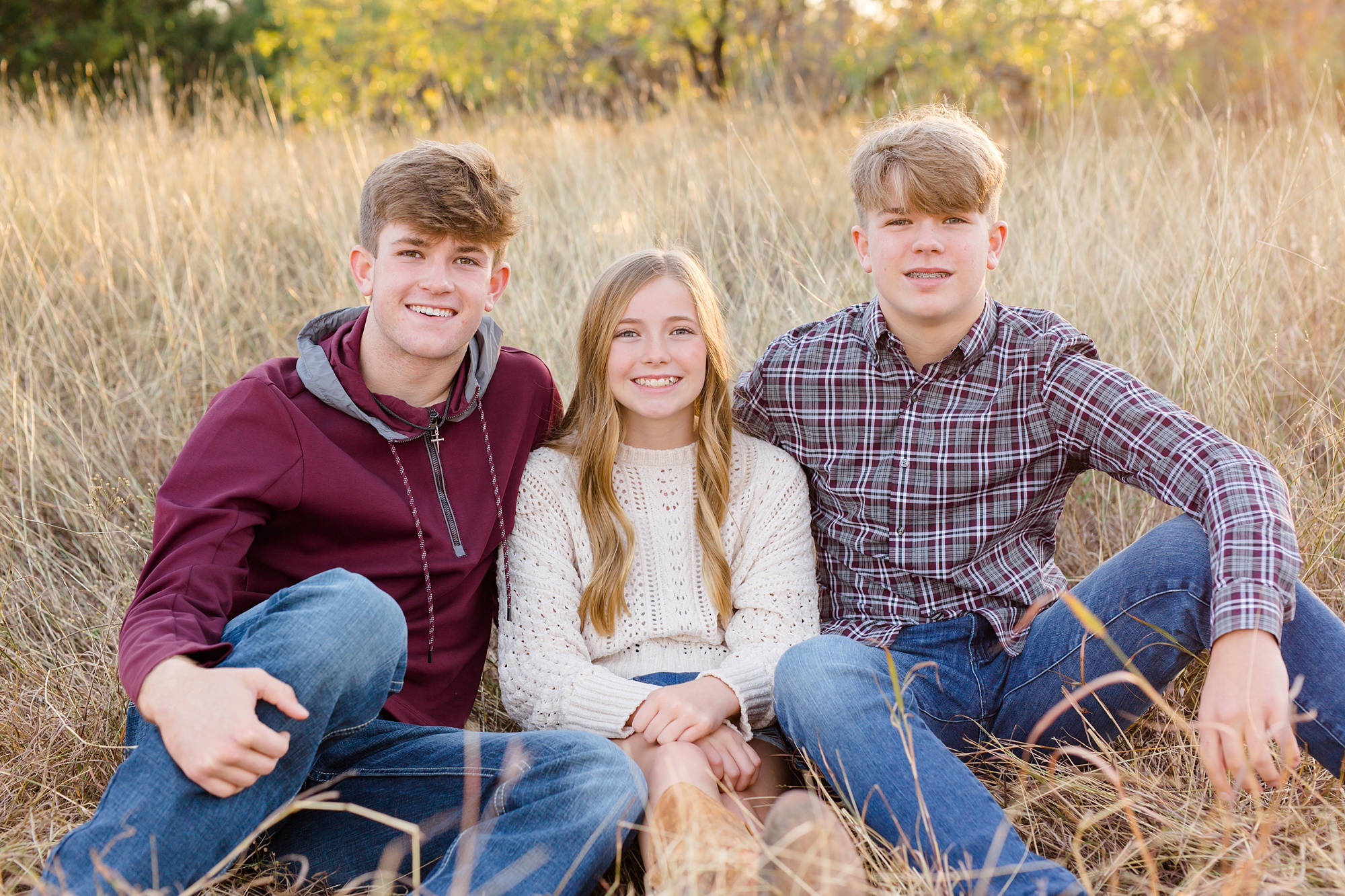 three siblings pose in grass during TX family session