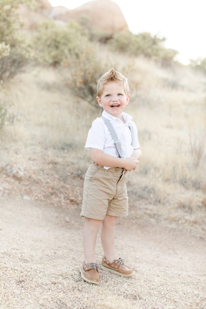 toddler in suspenders poses in desert