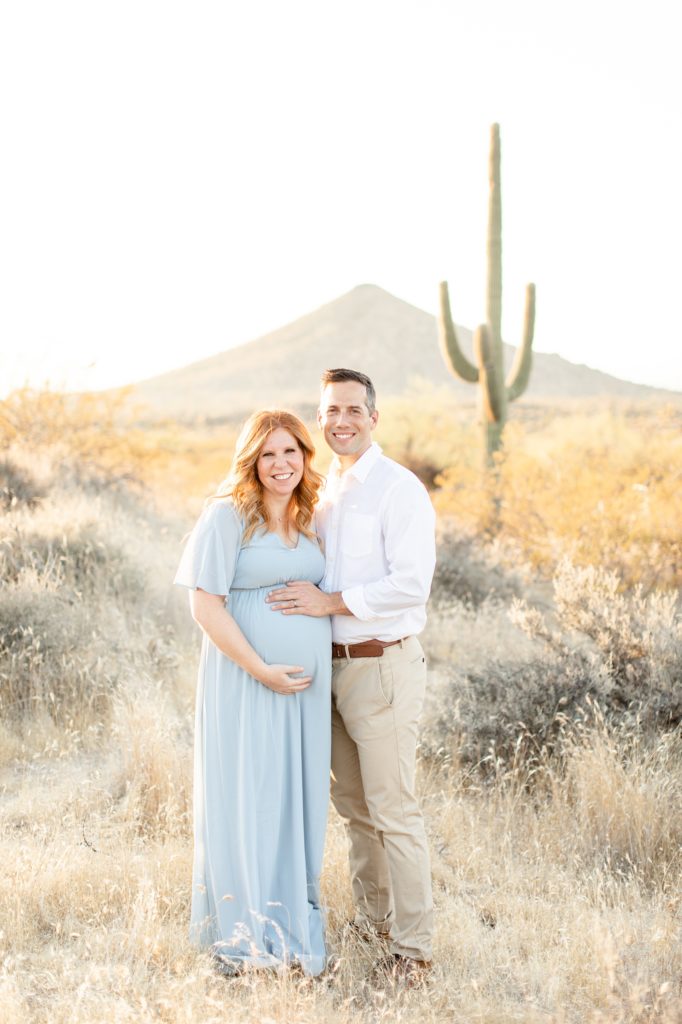 husband holds wife's belly in blue dress