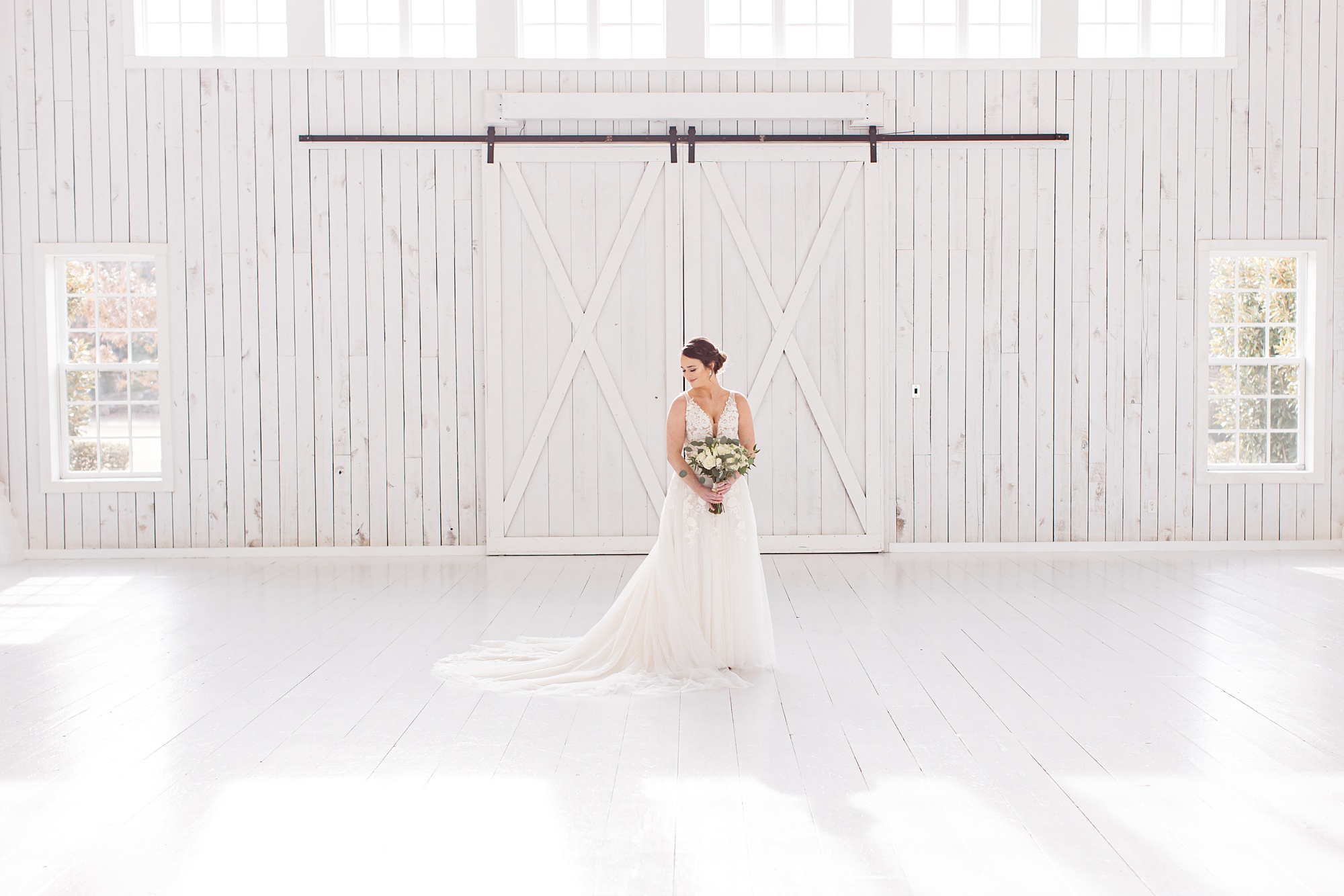bride holds bouquet in front of barn doors during White Sparrow bridal portraits