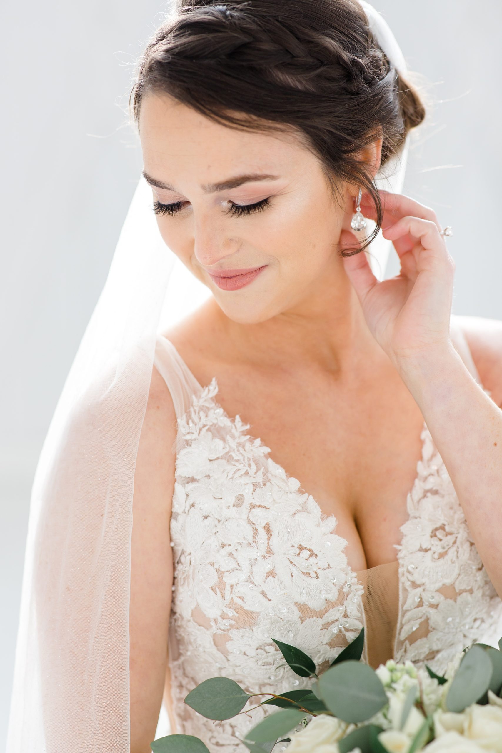 bride holds earring during portraits at the White Sparrow
