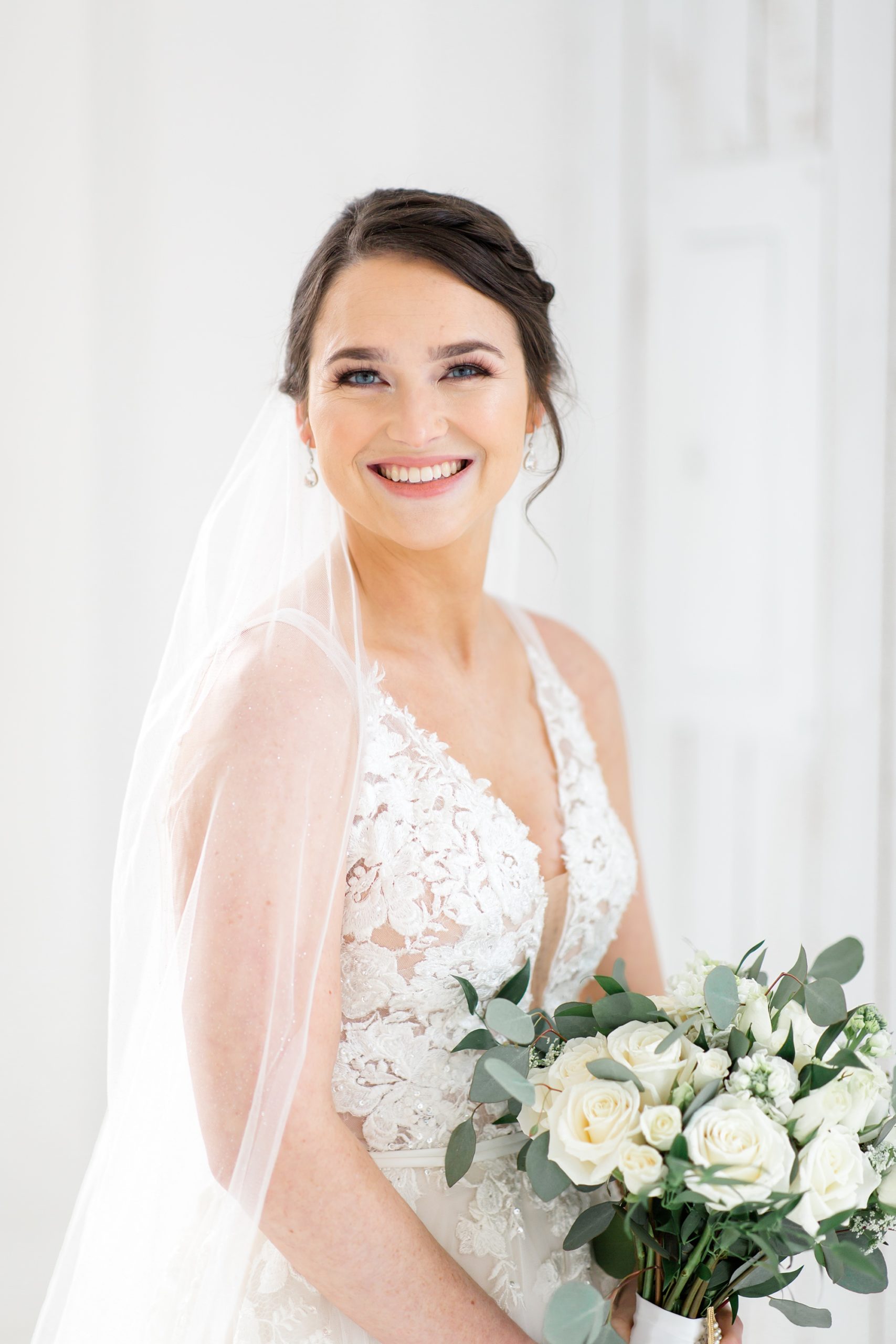 bride holds bouquet with cathedral veil wrapped around shoulder