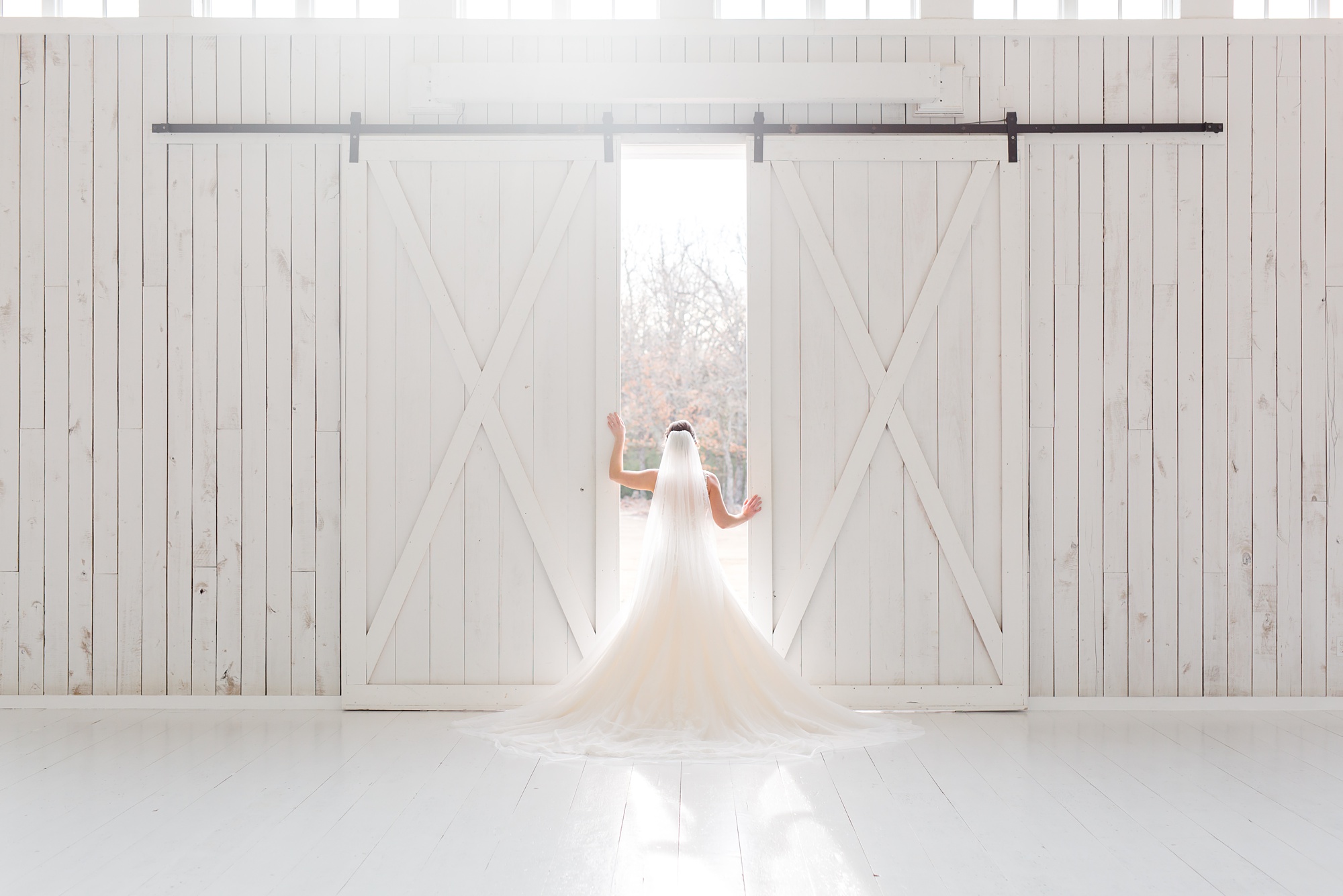bride looks out barn doors at the White Sparrow
