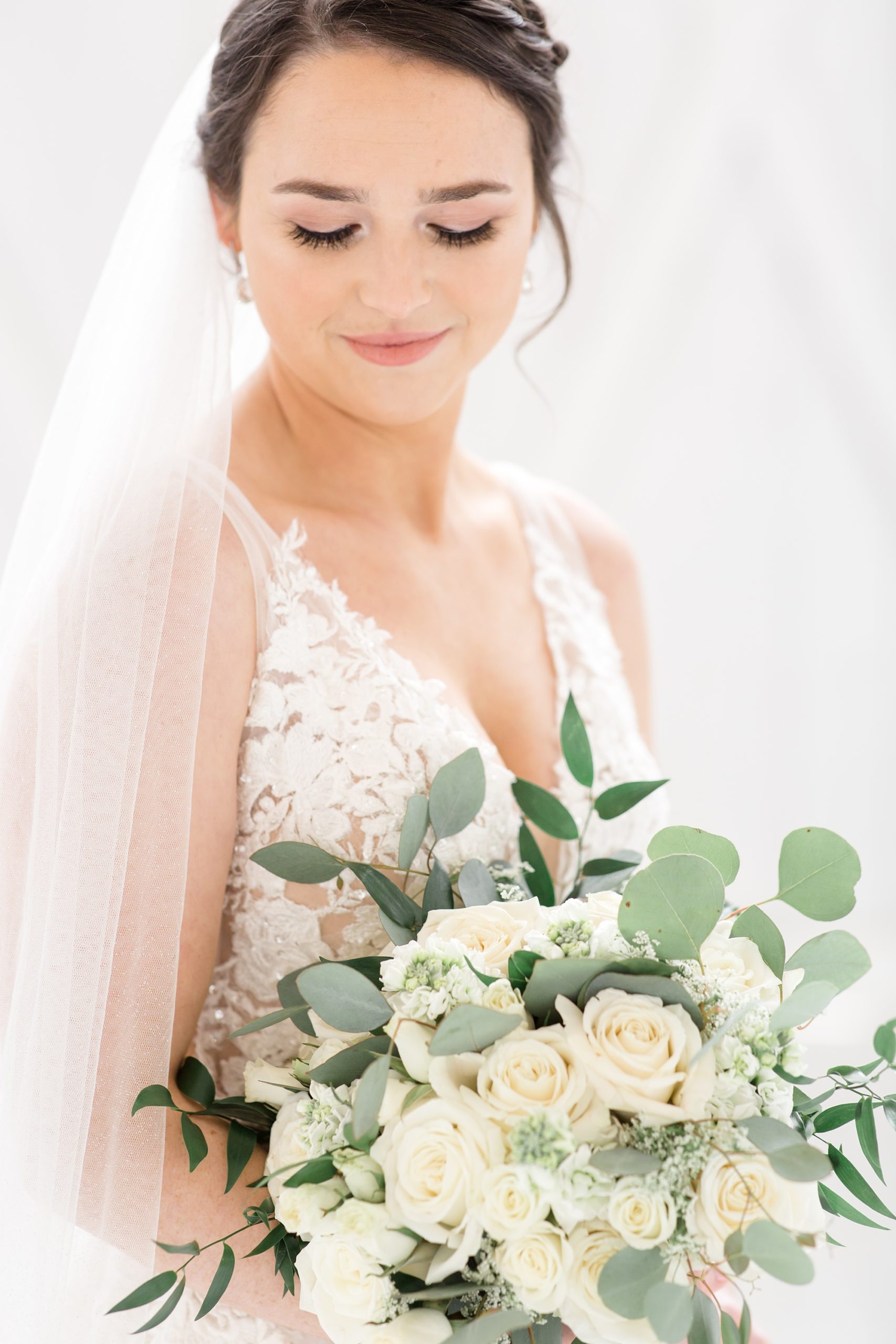 southern bride looks down at bouquet of white flowers