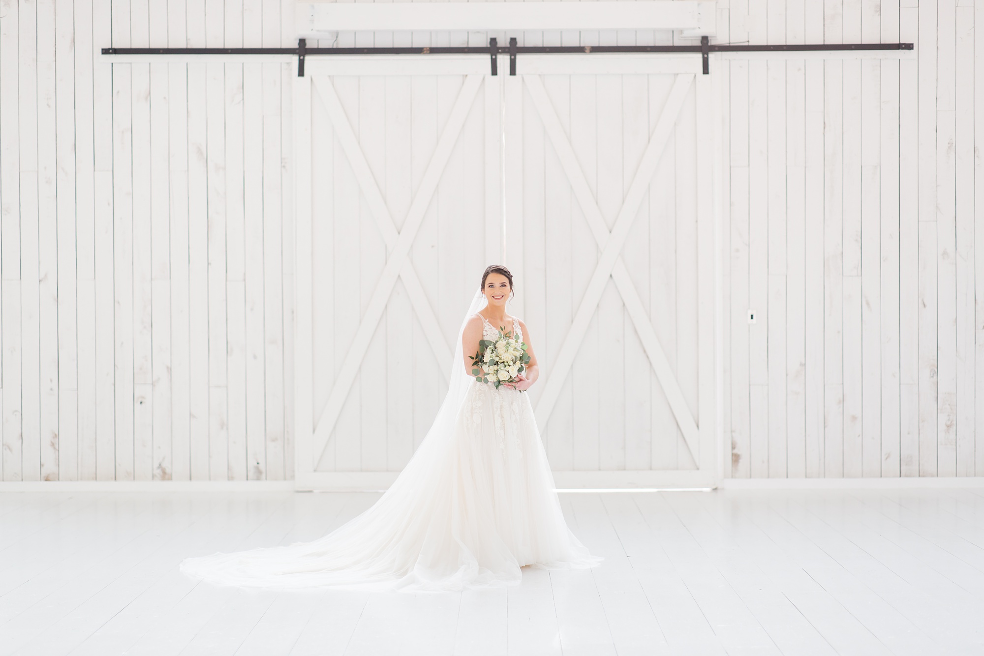 bride poses in front of white doors at the White Sparrow