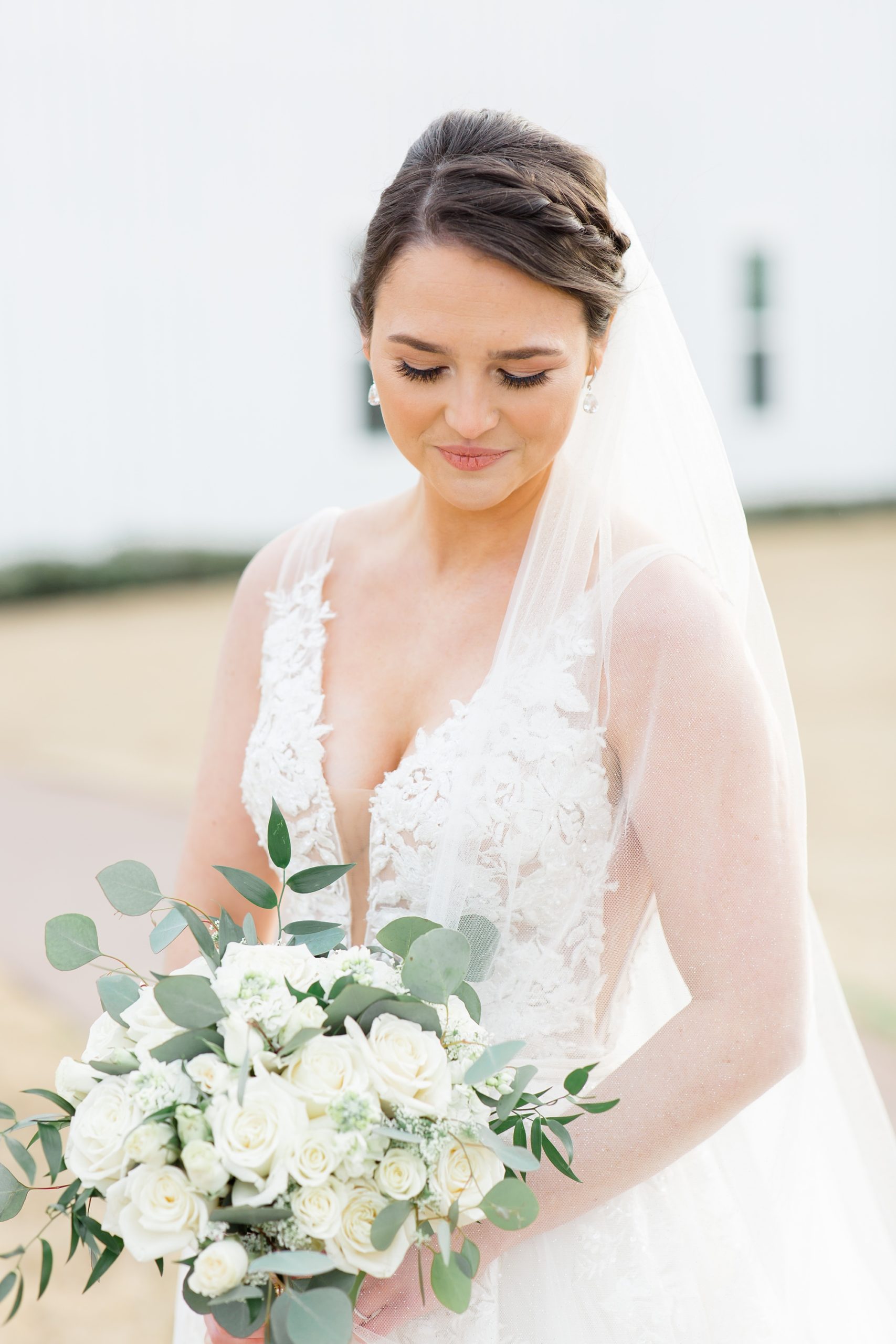 bride-to-be looks down at bouquet of white flowers