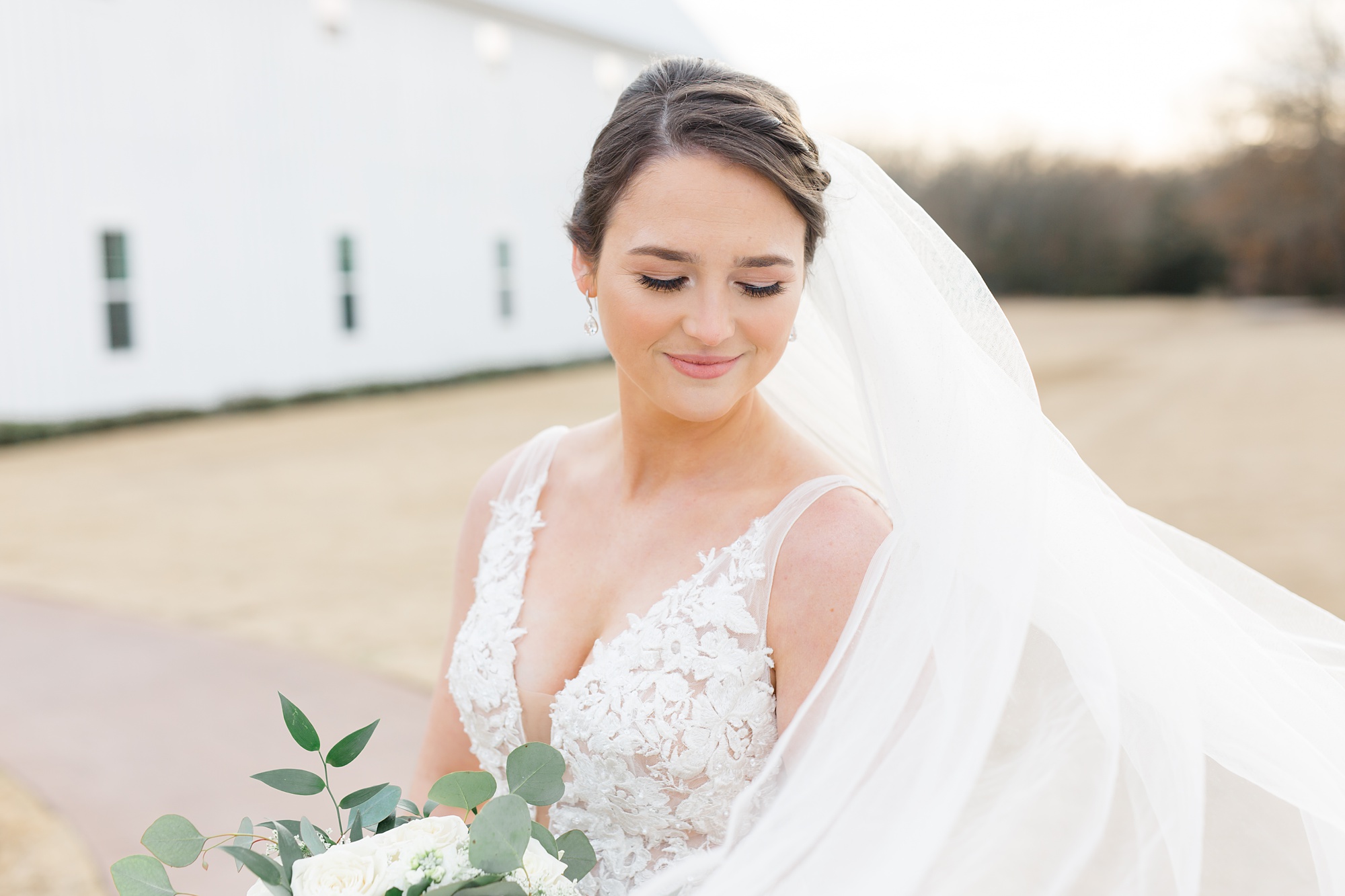 bride looks down over shoulder with veil floating around her