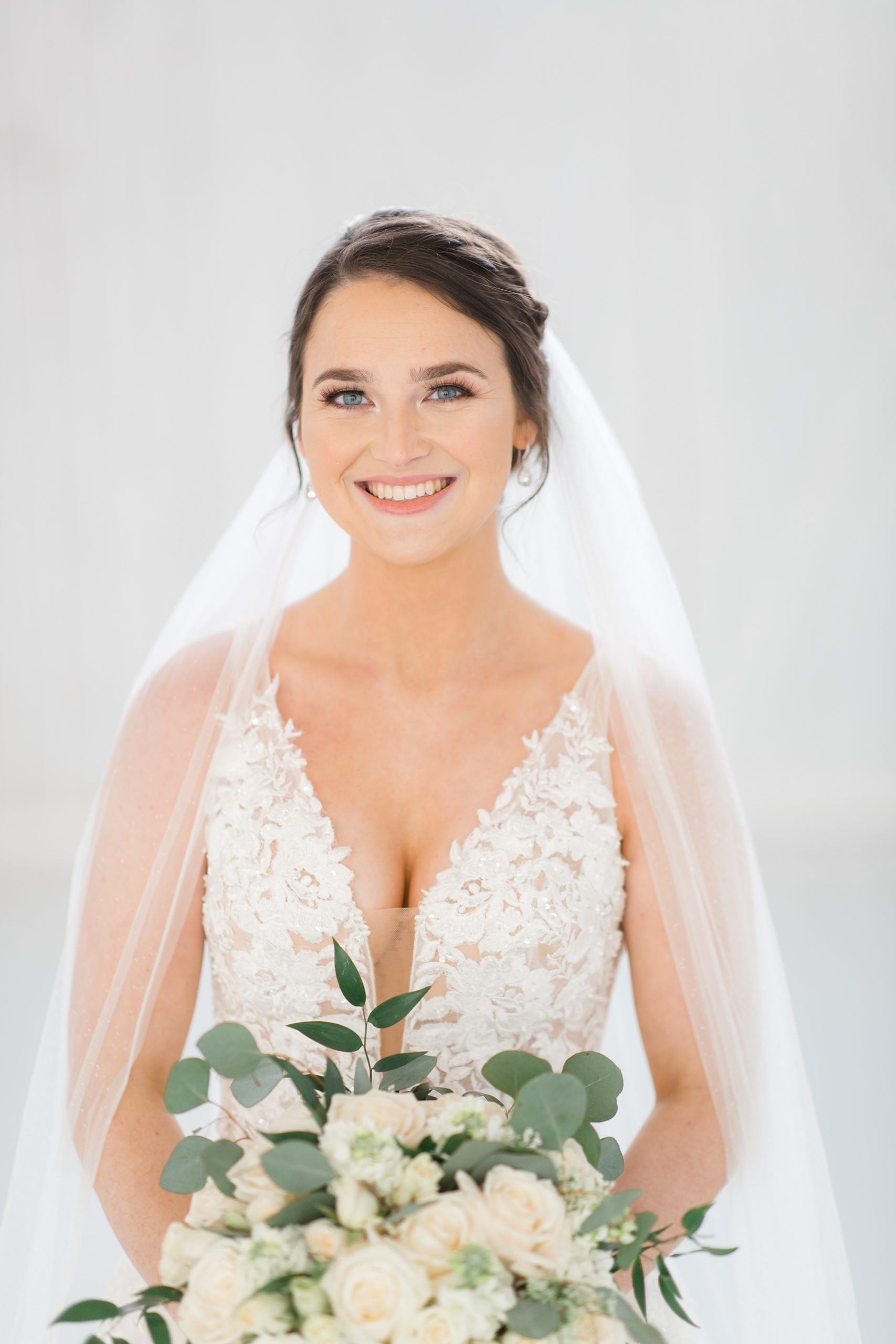 bride holds bouquet with veil around shoulders during White Sparrow bridal portraits