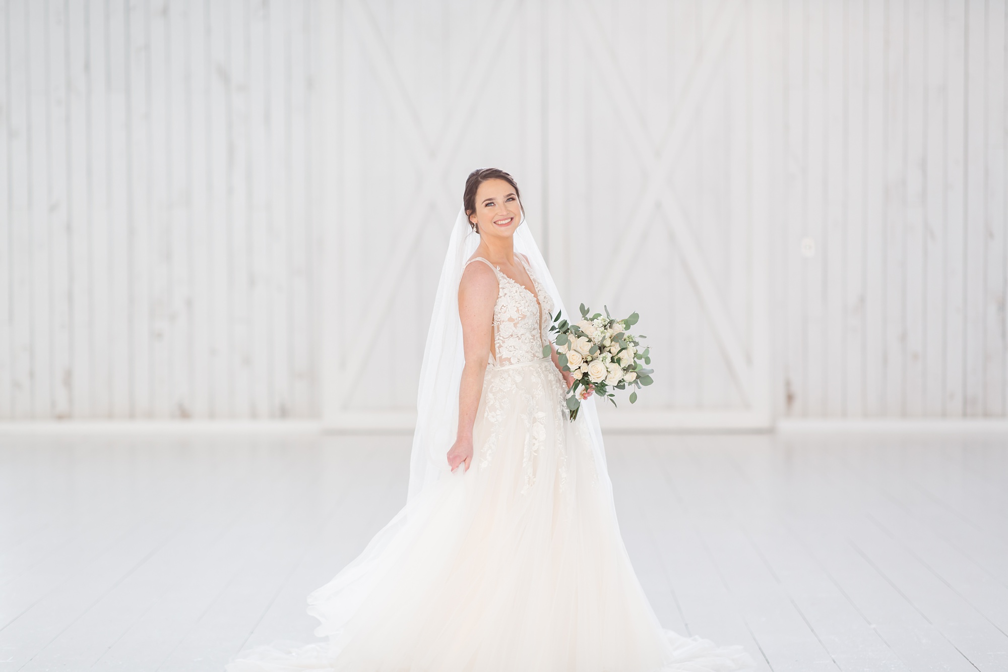 bride-to-be twirls wedding dress in front of farmhouse doors at The White Sparrow