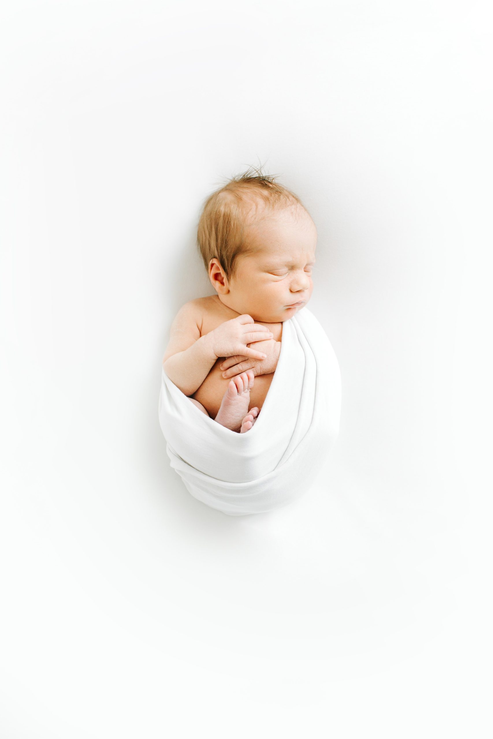 baby sleeps in white swaddle during Dallas newborn portraits 