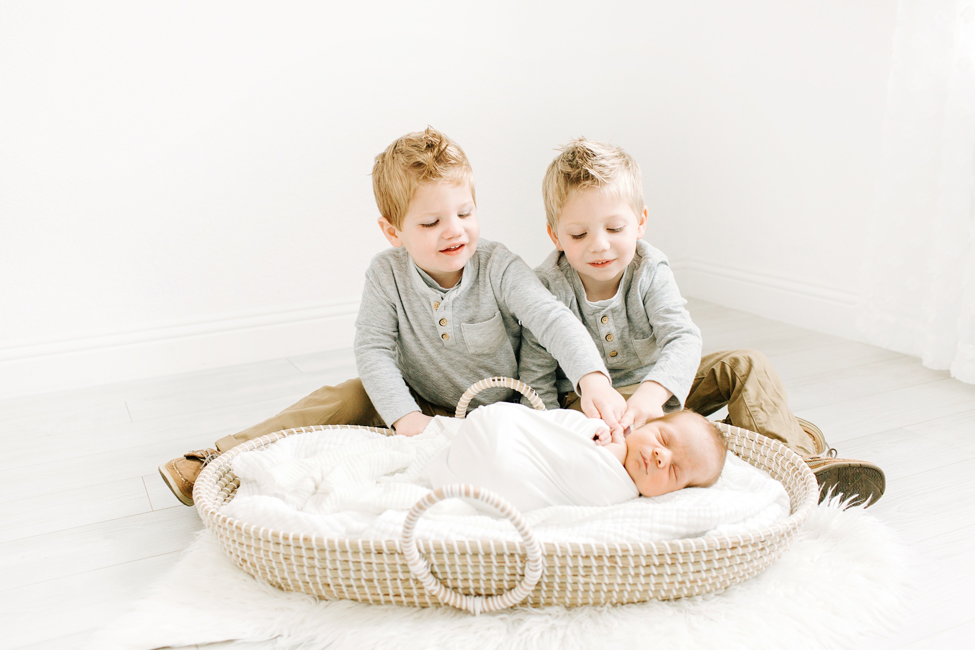 brothers look at baby during newborn session in Texas