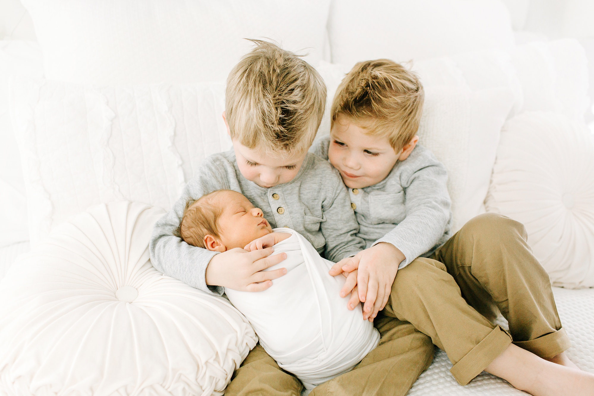 big brothers hold baby during newborn photos 