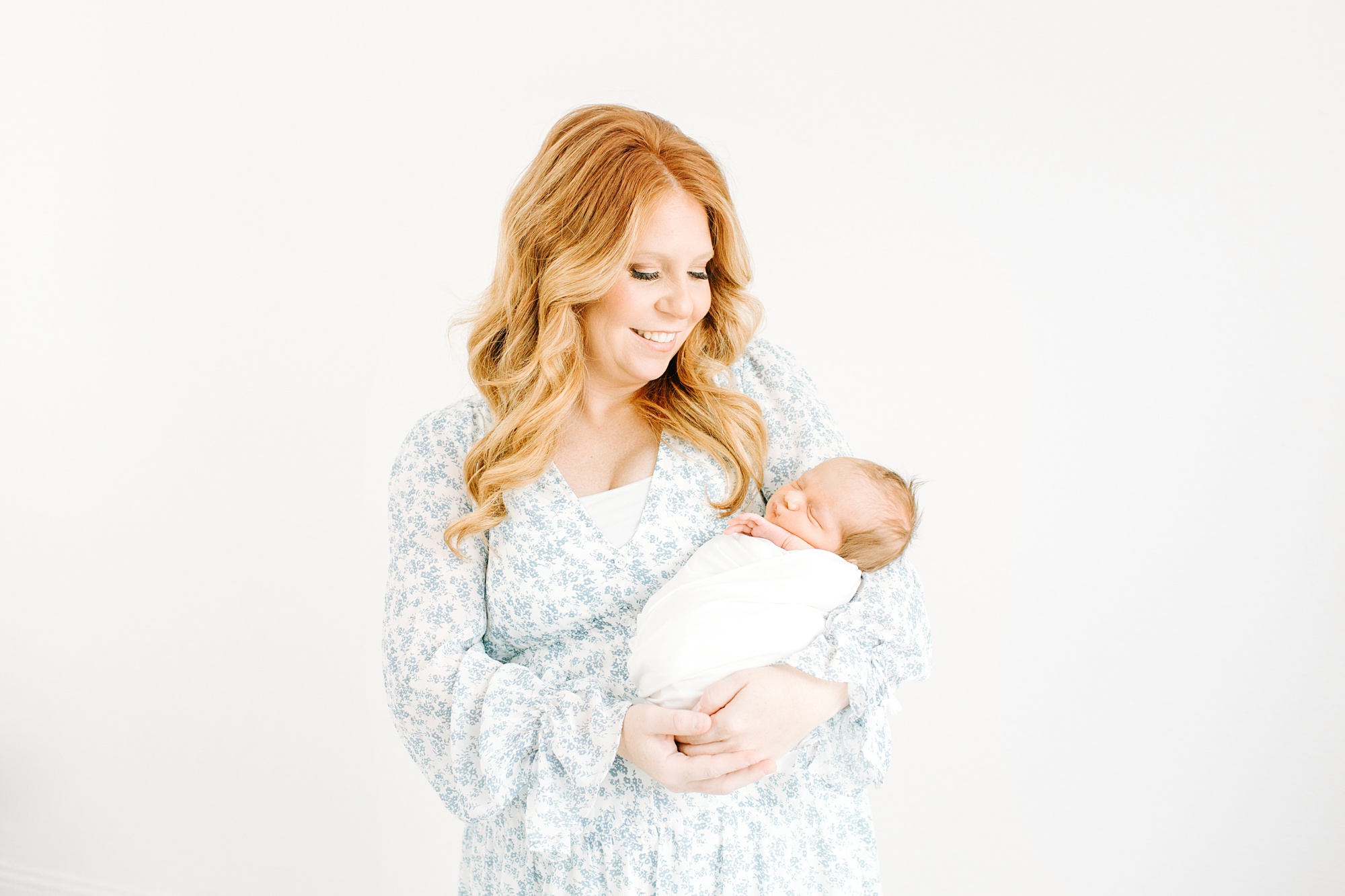 mom holds baby boy in white swaddle during newborn session