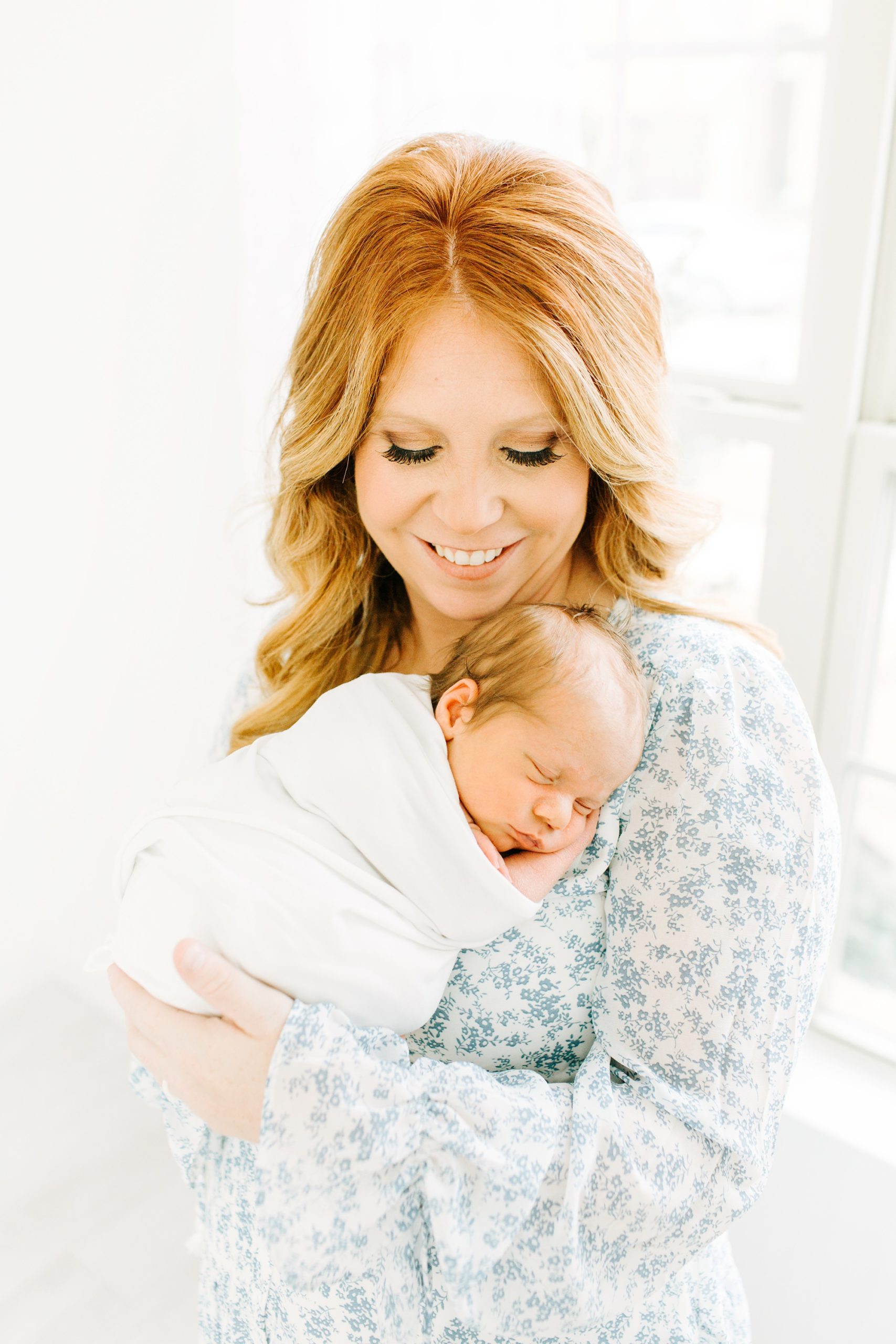 mom holds baby boy on shoulder during Dallas newborn portraits