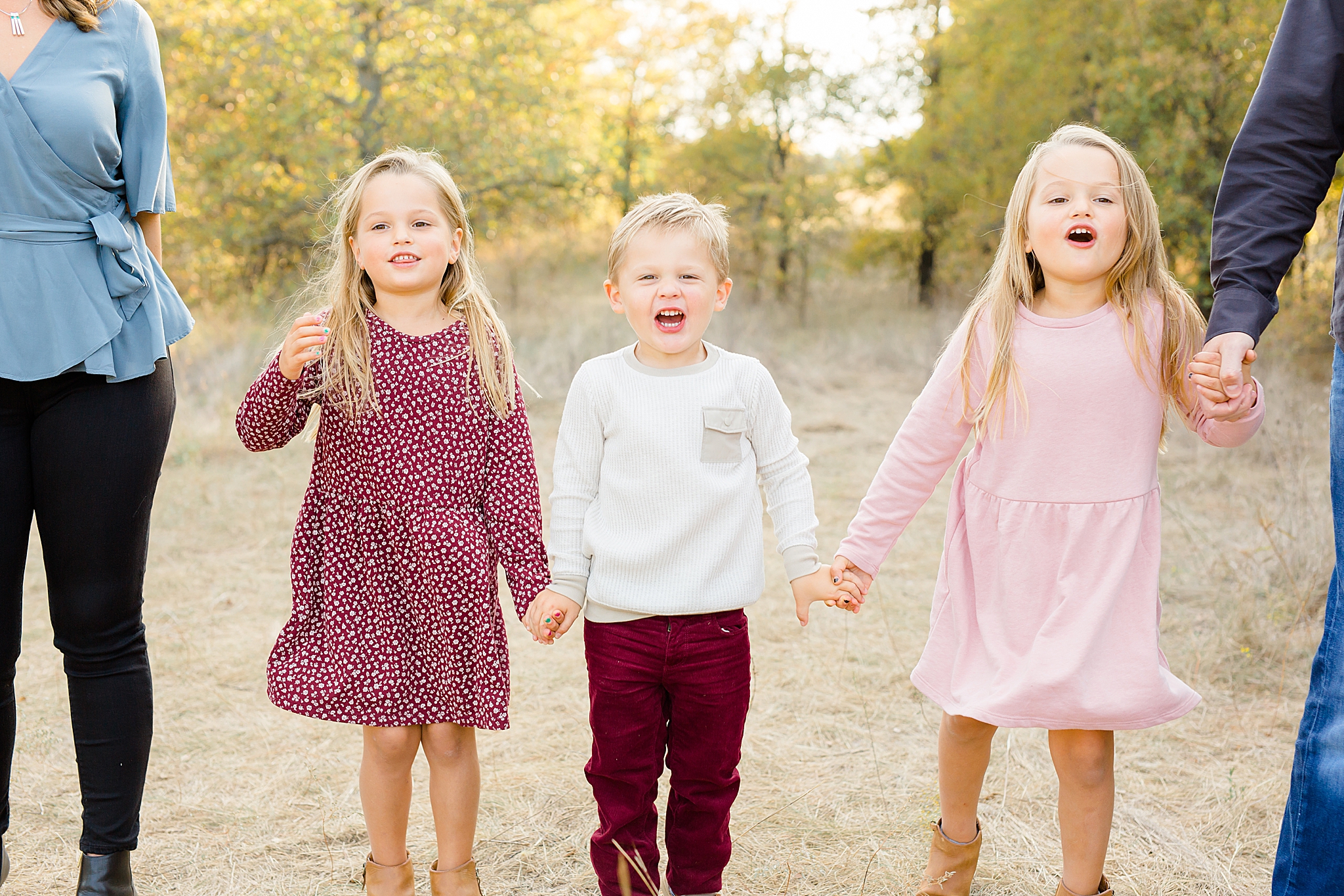 siblings hold hands and laugh during family photos in Texas