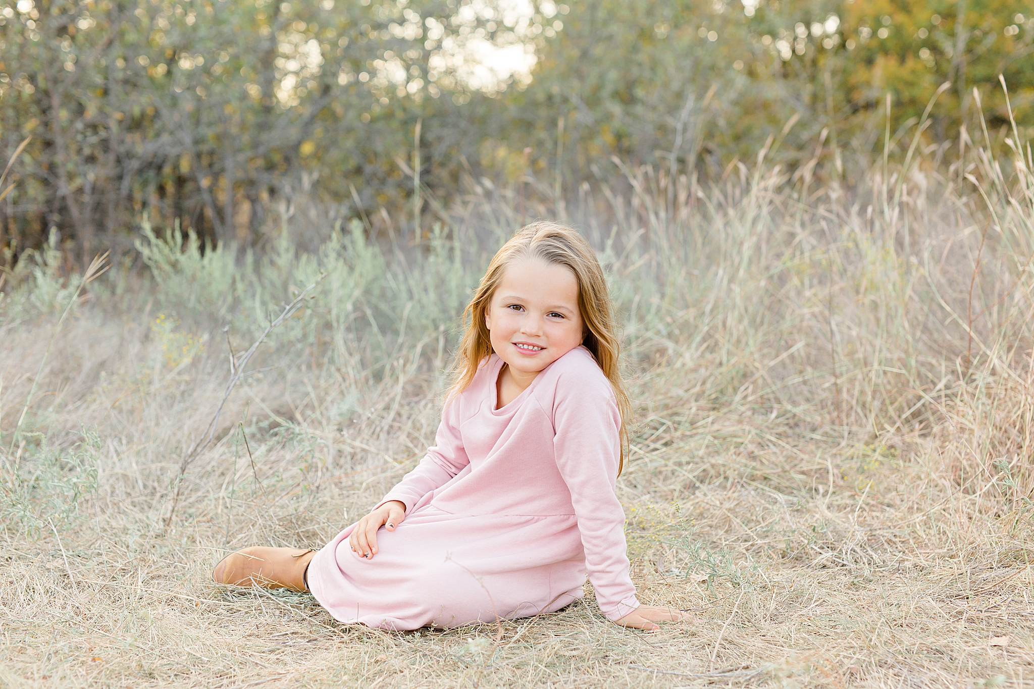 daughter in pink dress sits by grass at Murrell Park