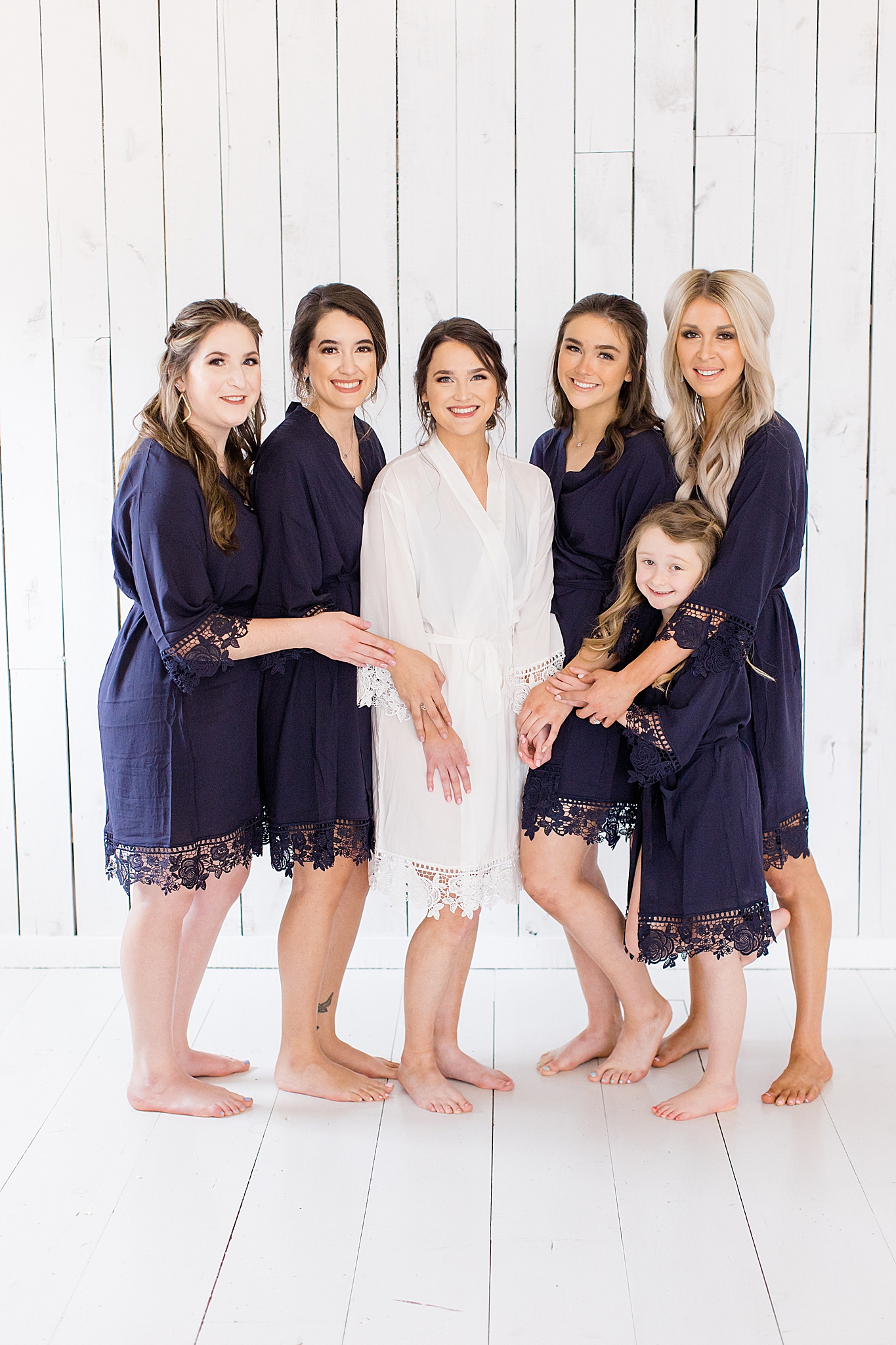 bride gets ready for The White Sparrow wedding with bridesmaids in navy blue robe