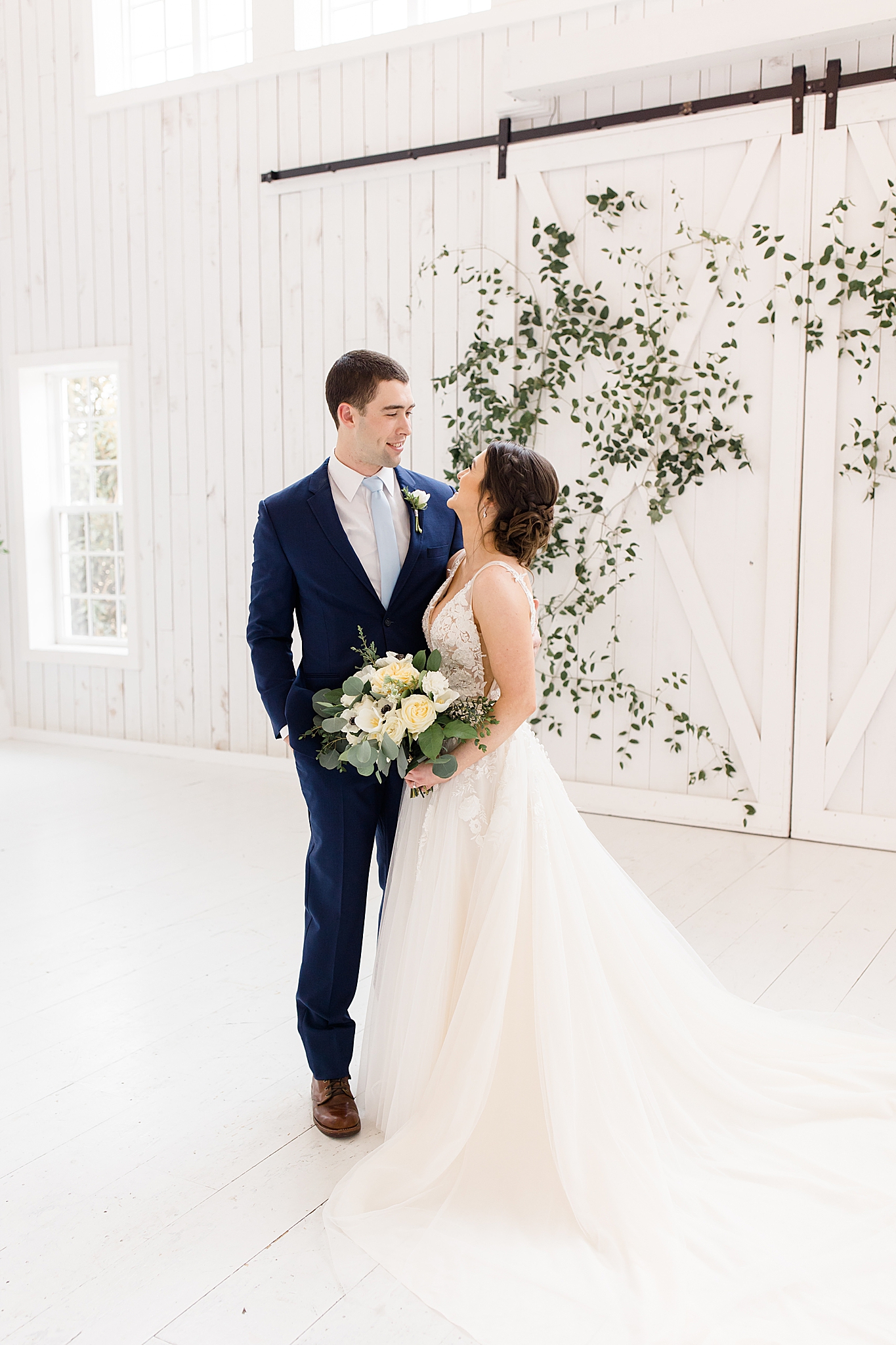 bride and groom pose in front of hanging greenery at The White Sparrow