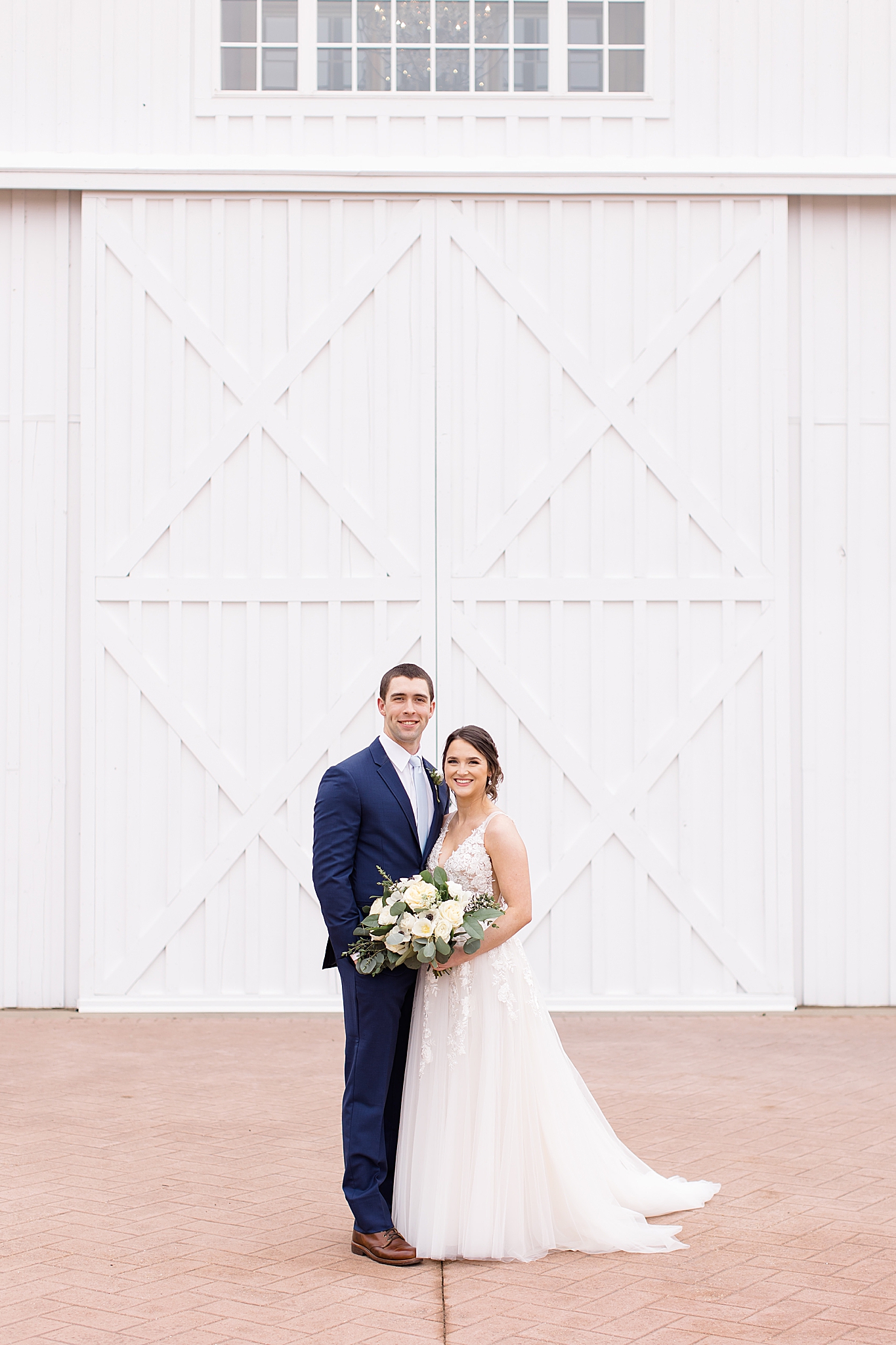 bride and groom pose in front of white barn doors in Dallas TX