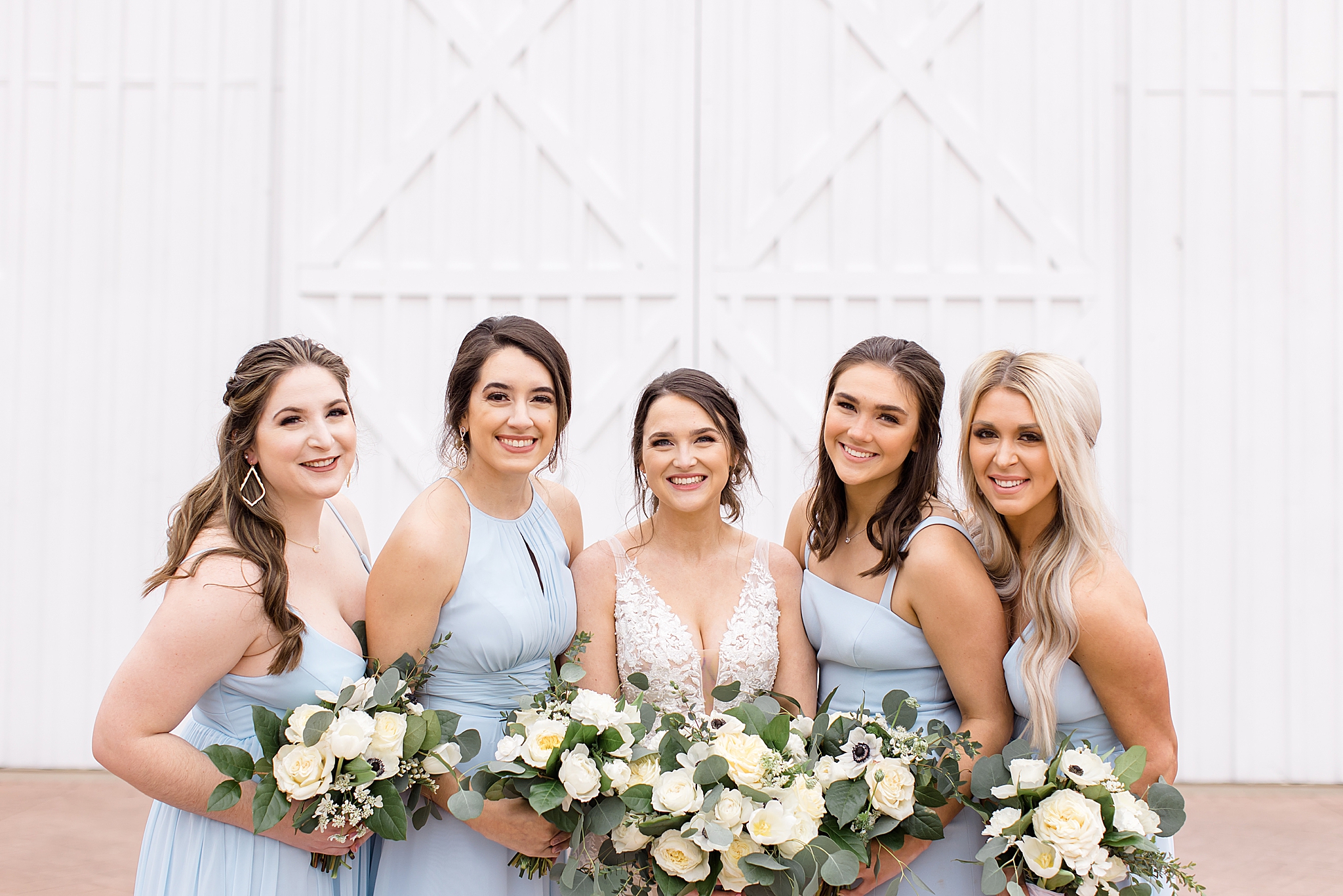 bridesmaids hug bride wearing light blue gowns
