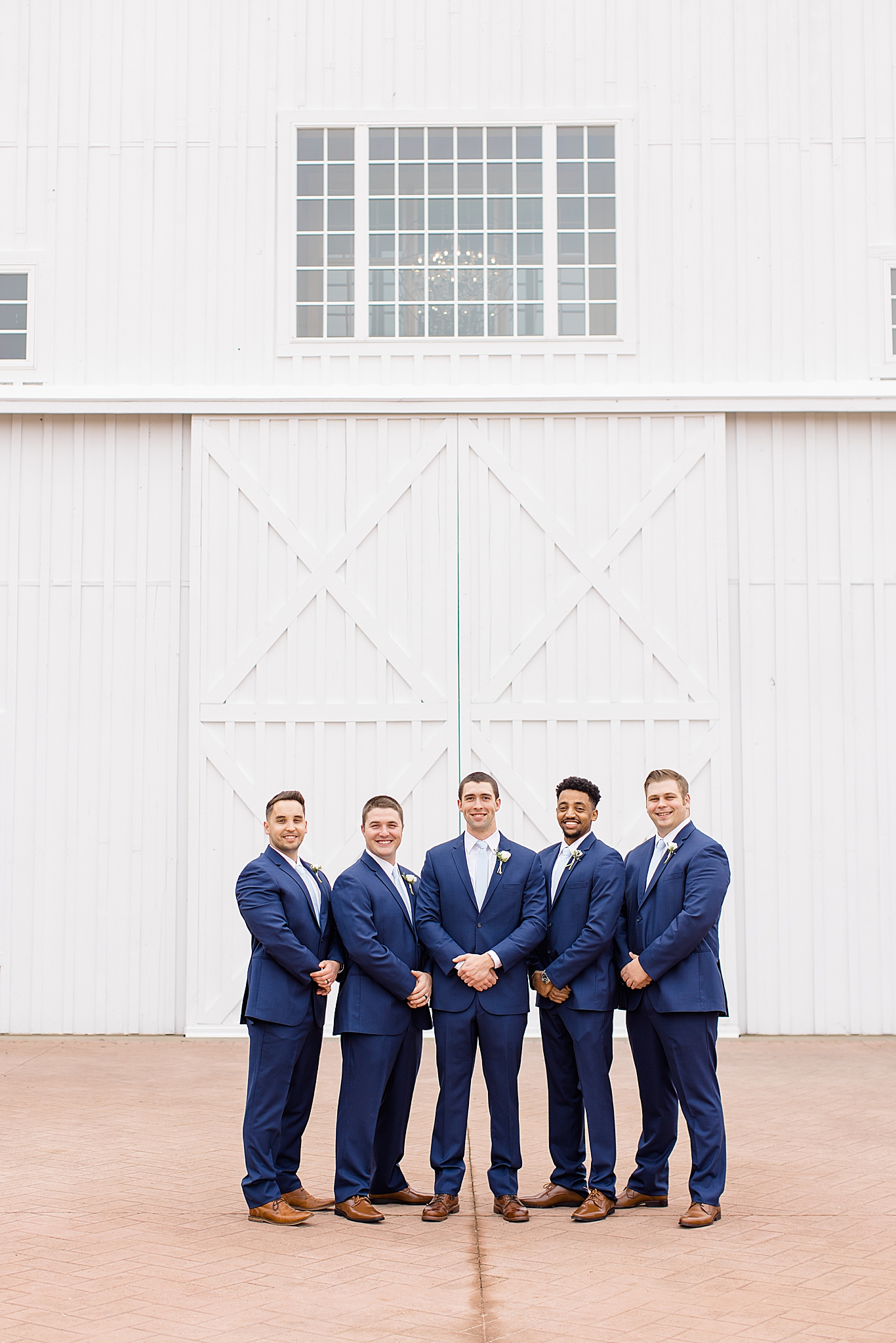 groom poses with groomsmen in navy suits