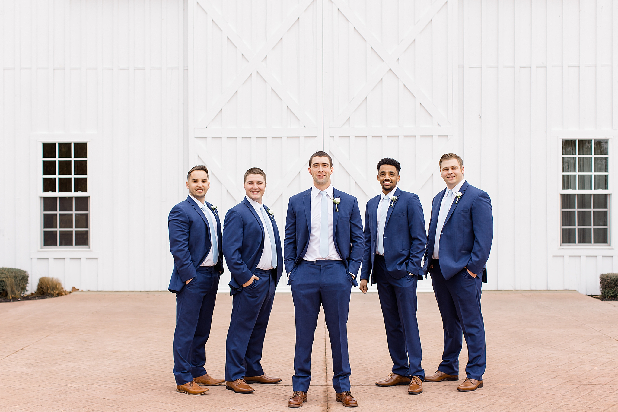 groom in navy suit poses with four groomsmen outside The White Sparrow