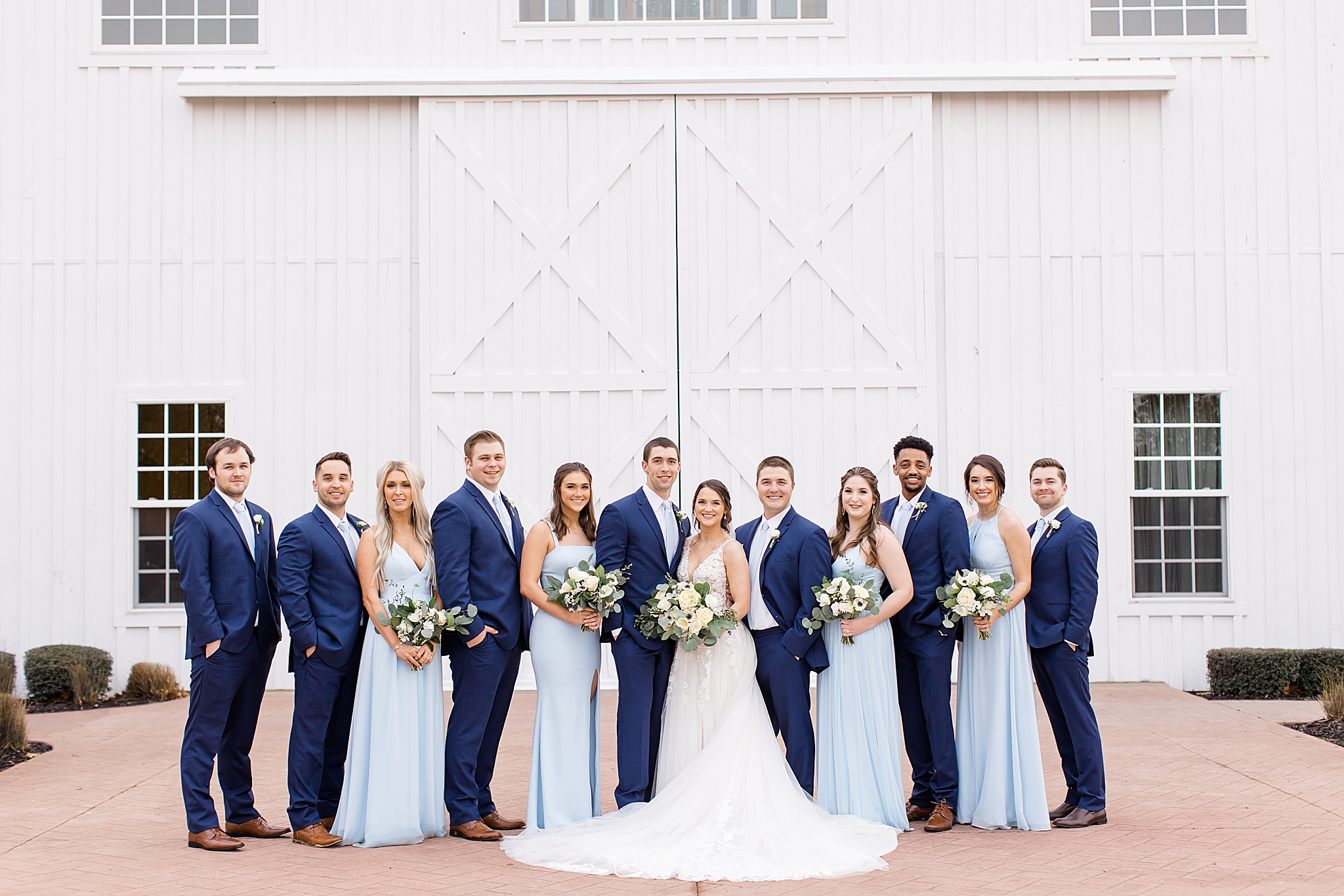 bridal party poses outside white door at The White Sparrow